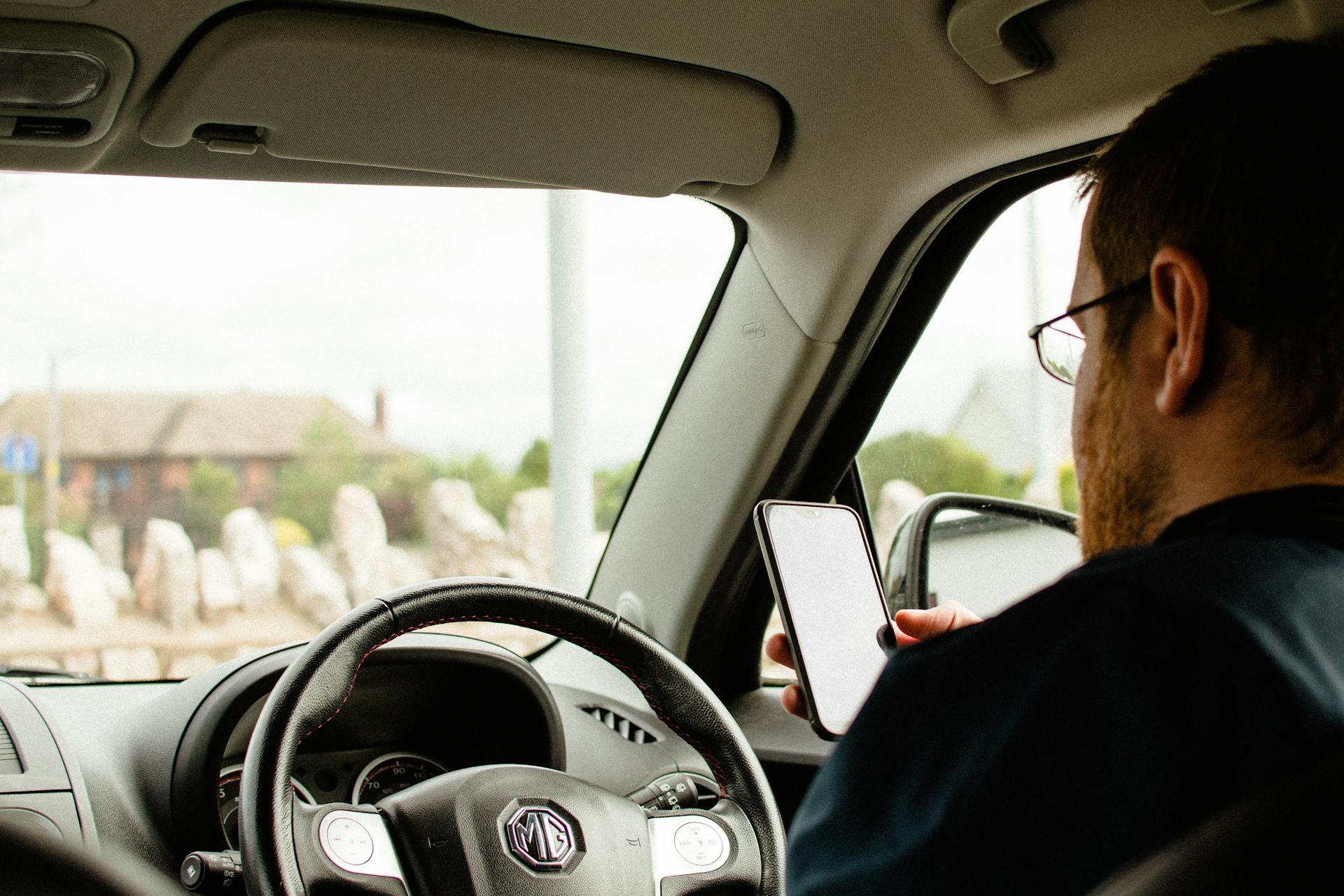 A man holding his phone while sitting in his car | Source: Pexels