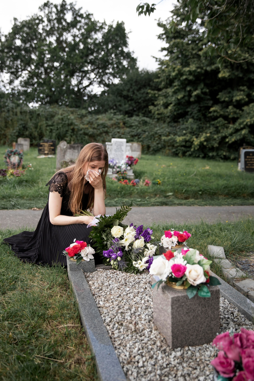 A woman mourning beside a loved one's grave | Source: Freepik