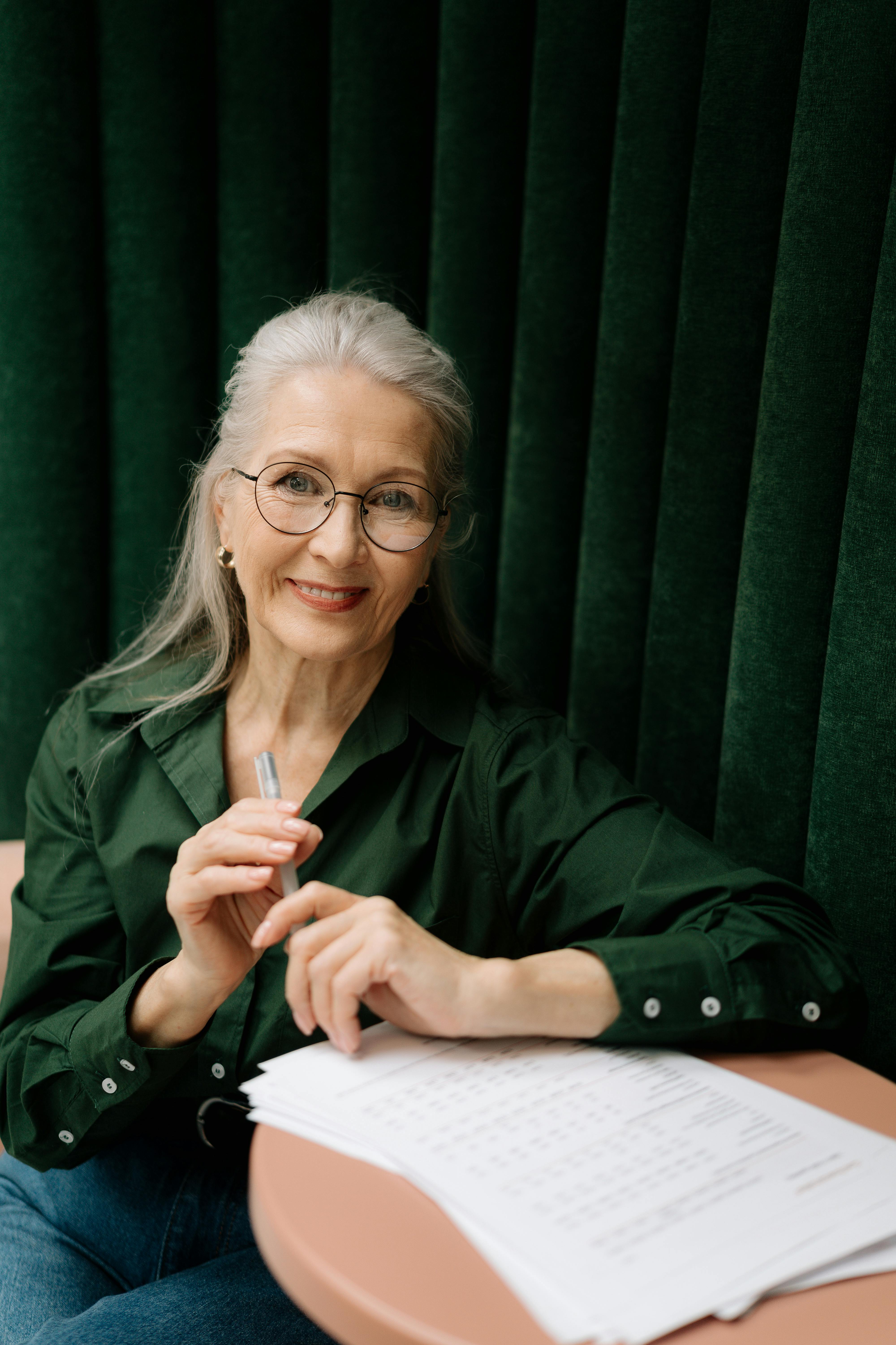 A smiling older woman sitting at a table | Source: Pexels