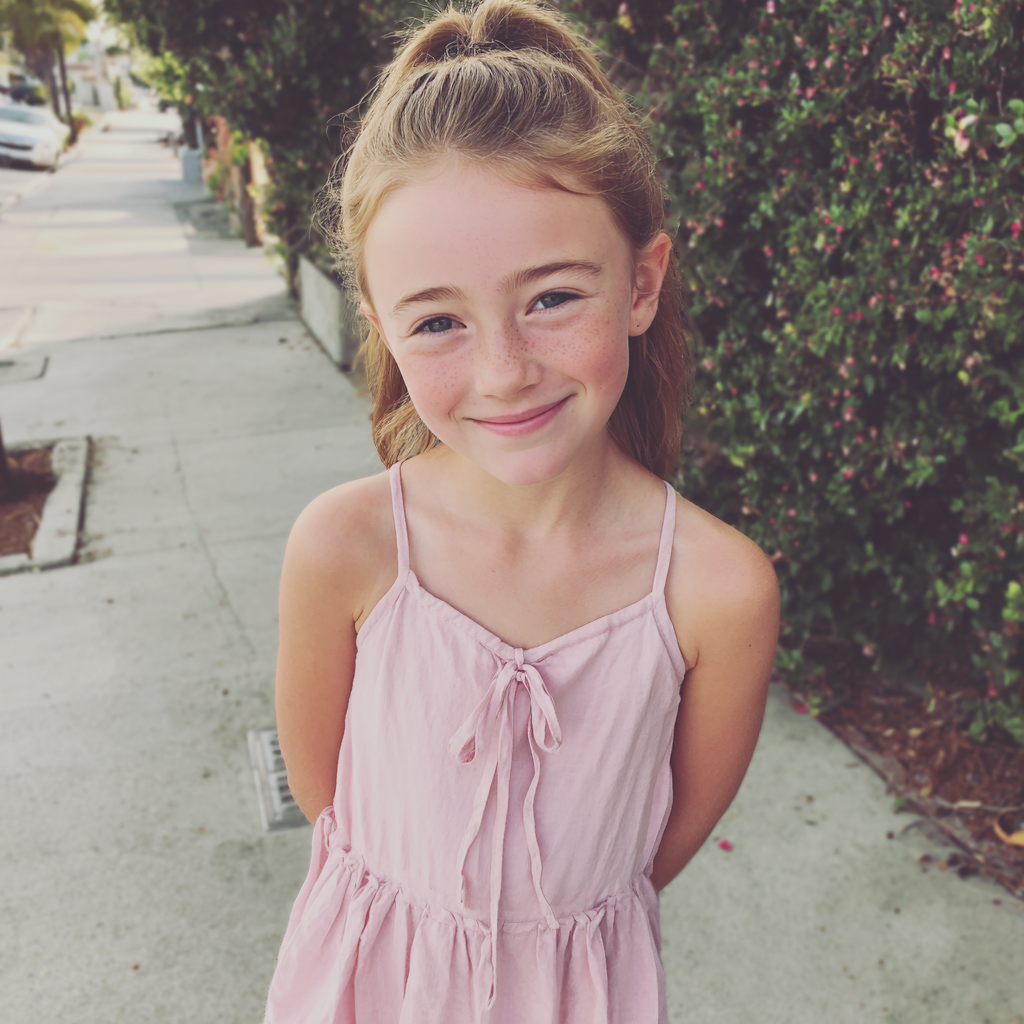A smiling little girl standing on a sidewalk | Source: No source