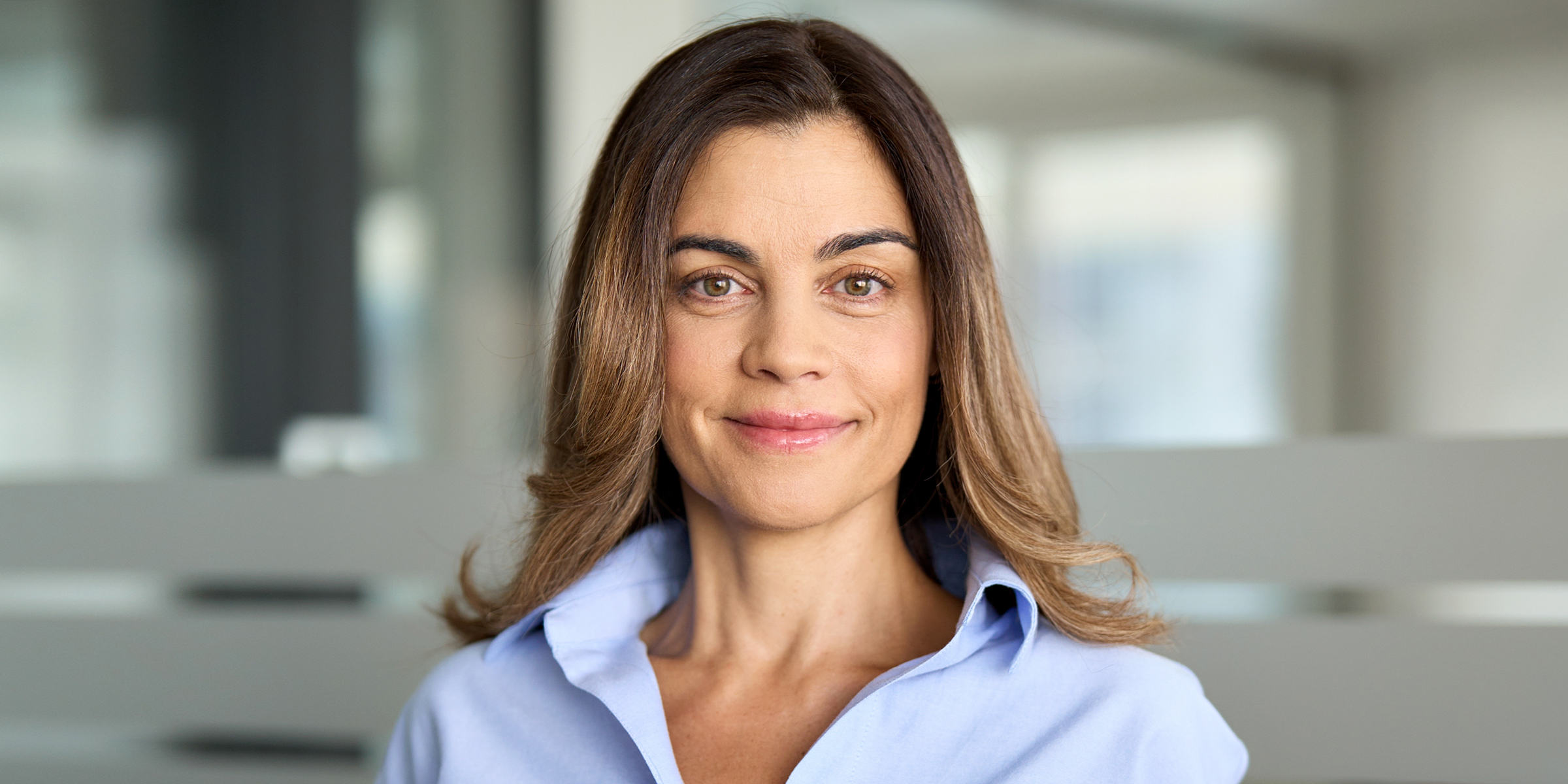 A smiling middle-aged woman standing in a modern office building | Source: Shutterstock