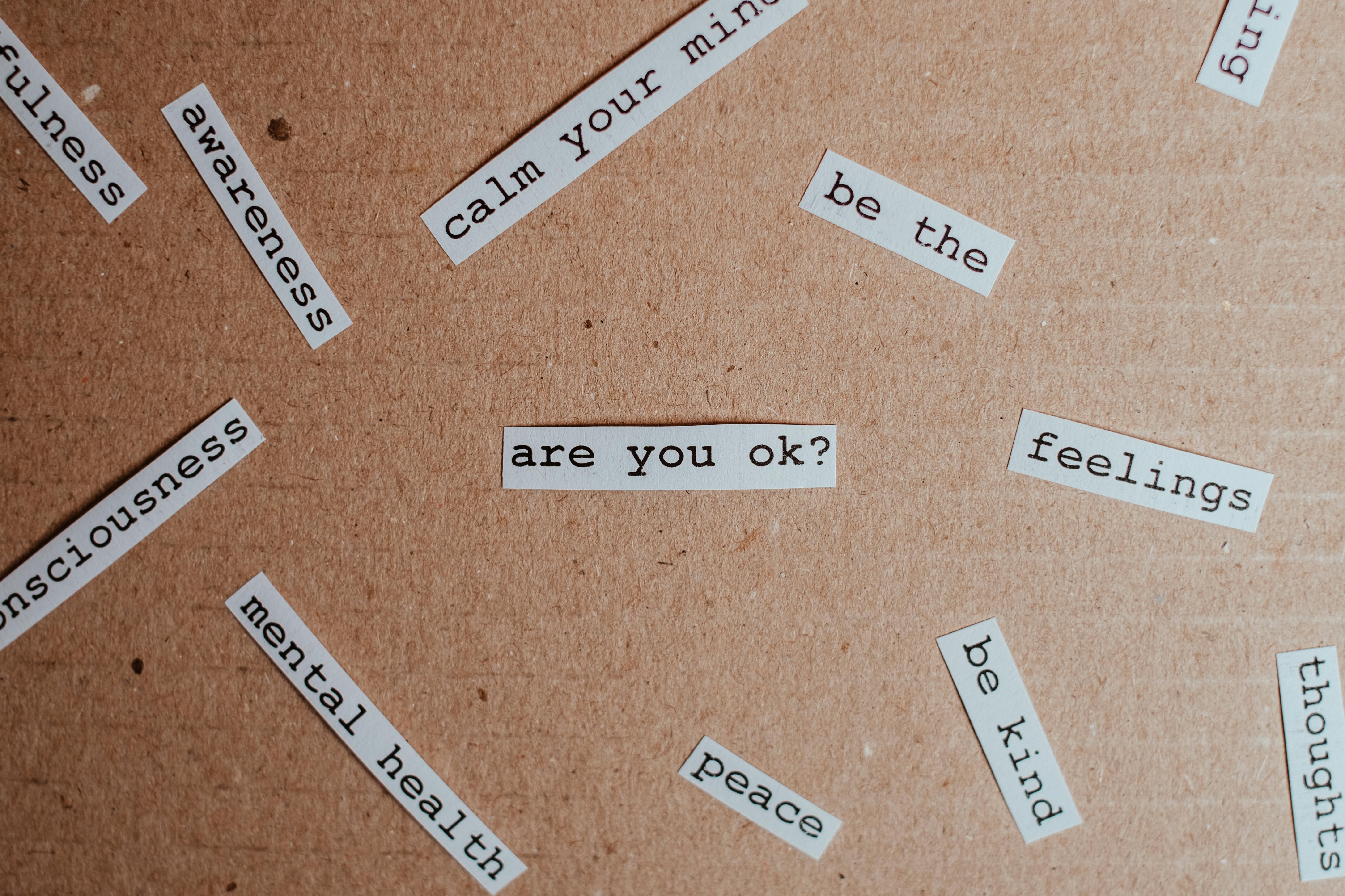Cut-out words related to mental health and mindfulness, arranged on a brown background | Source: Pexels