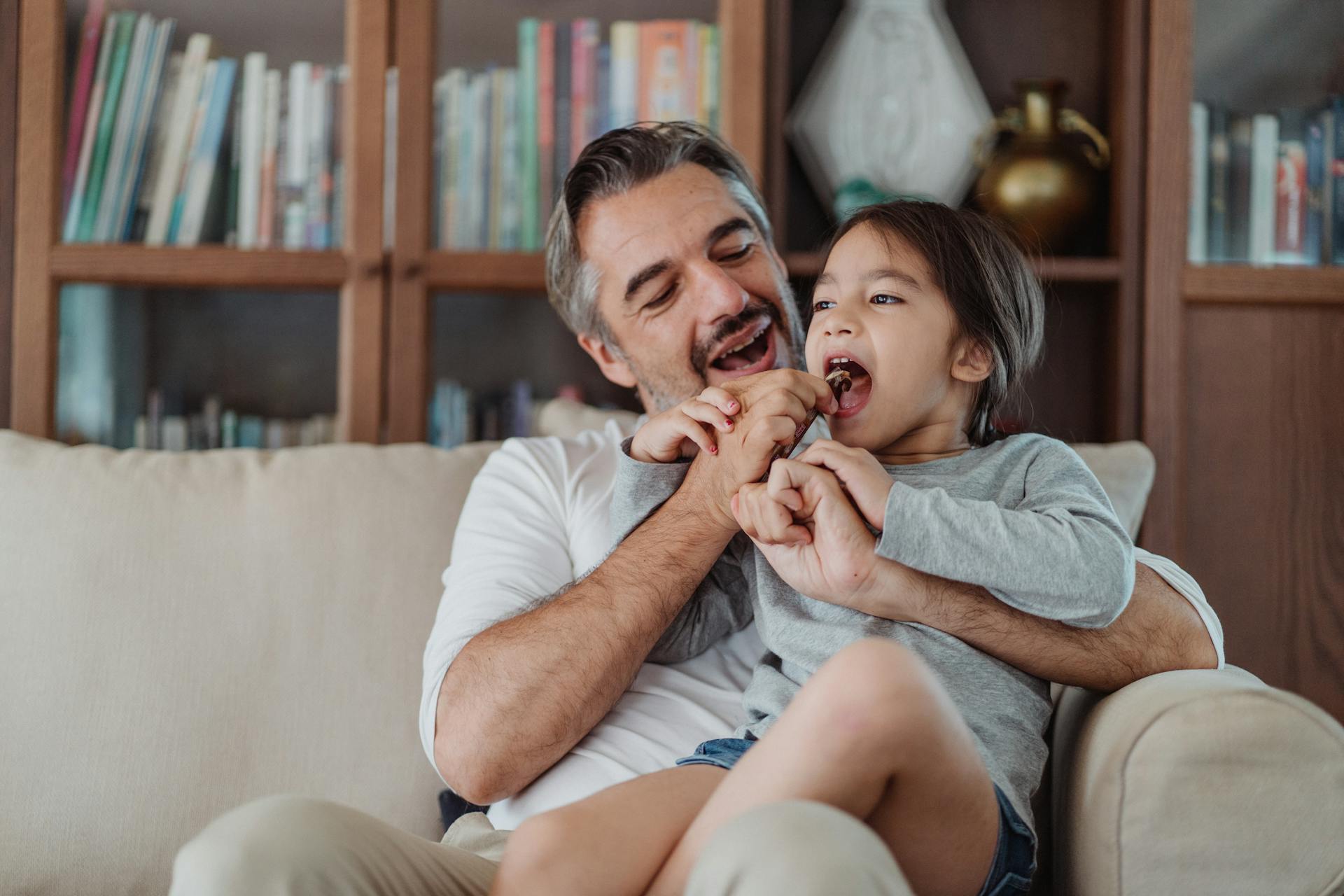 A man sharing candy with a little girl | Source: Pexels