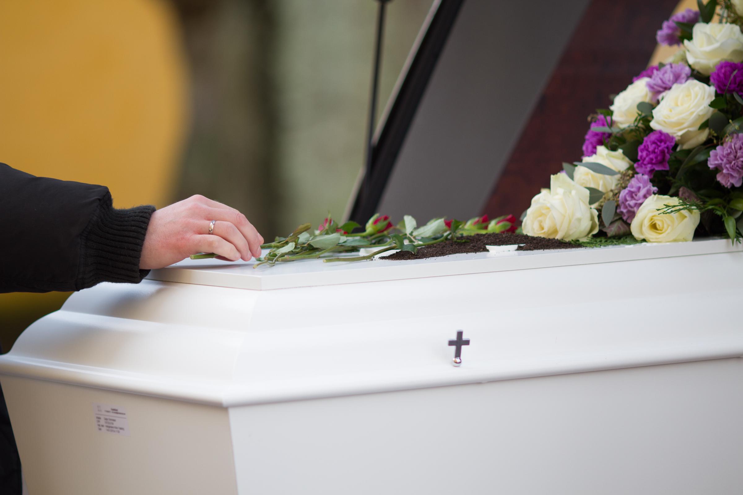 Closeup shot of a person hand on a casket | Source: No source