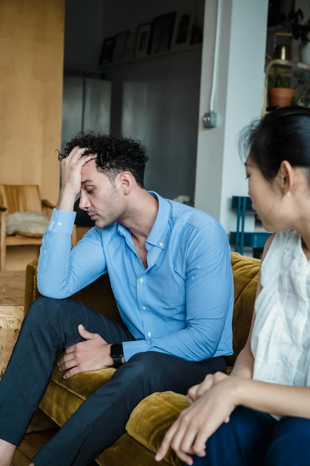 A tired man sitting on a couch with his wife | Source: Pexels