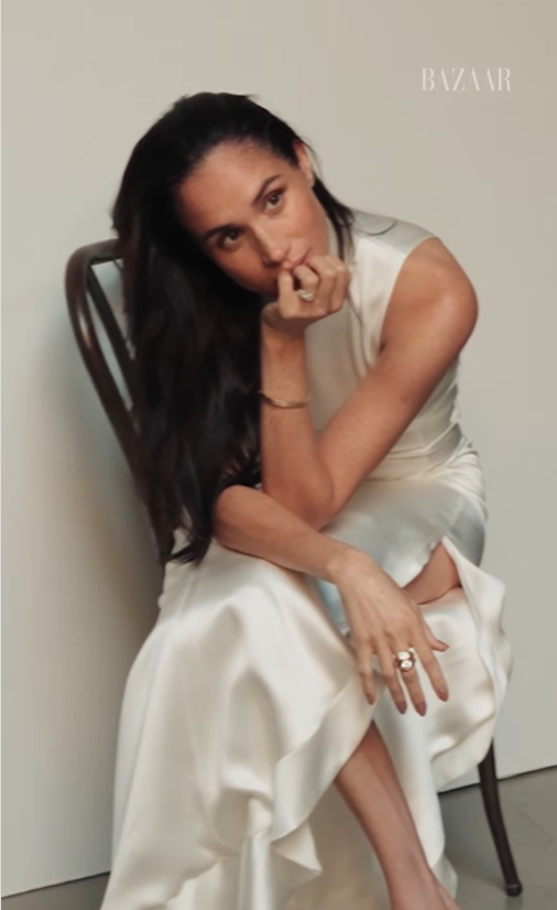 Meghan Markle is seated in a white dress, as seen from a video clip dated November 19, 2025. | Source: Instagram/harpersbazaarus