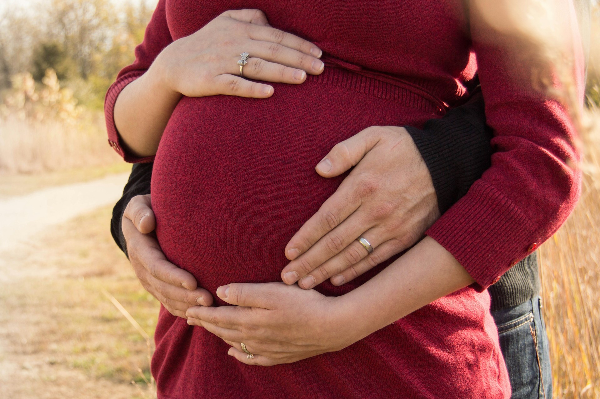A man embracing his pregnant partner from behind | Source: Unsplash