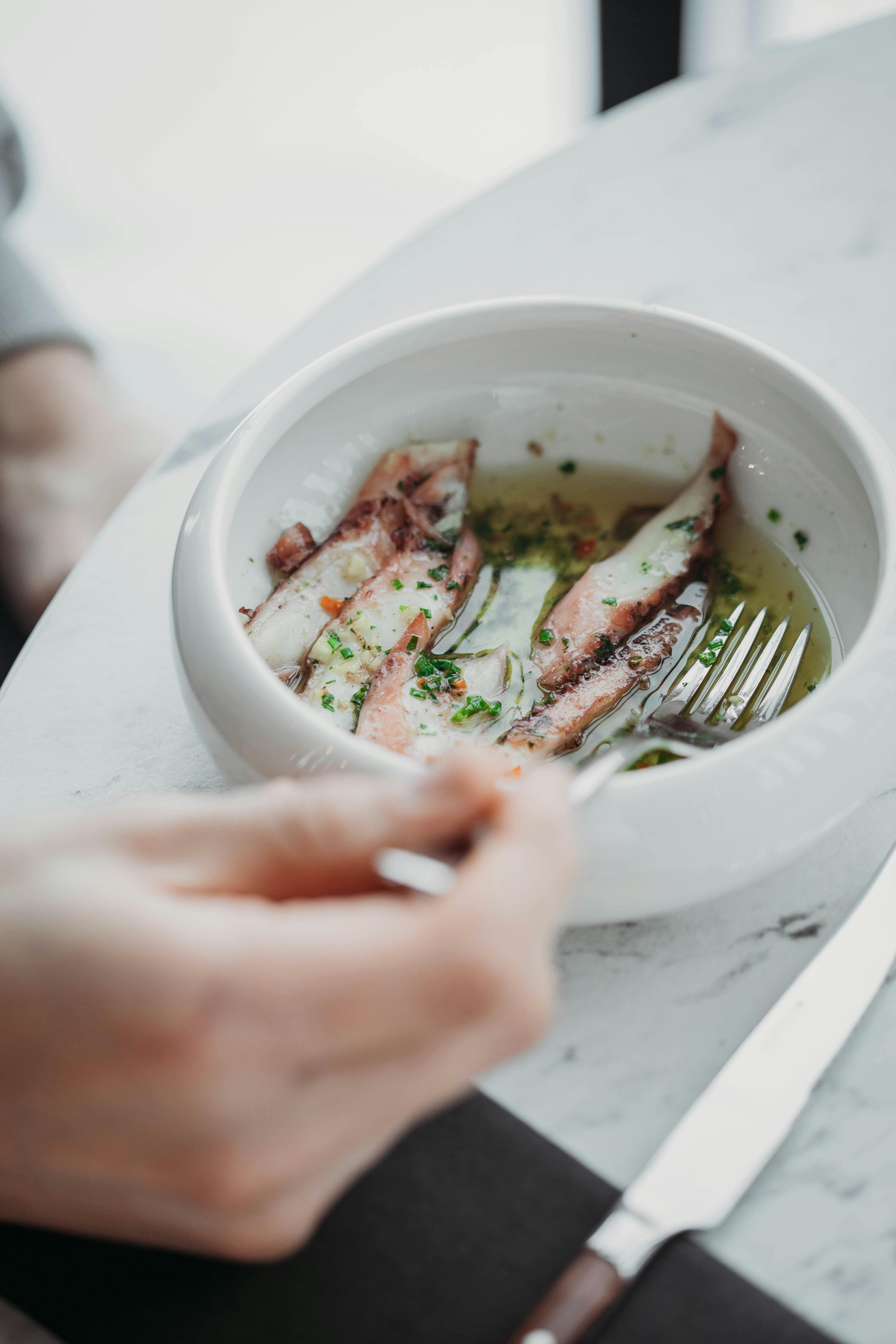 A person eating fish chunks from food using a fork | Source: Pexels