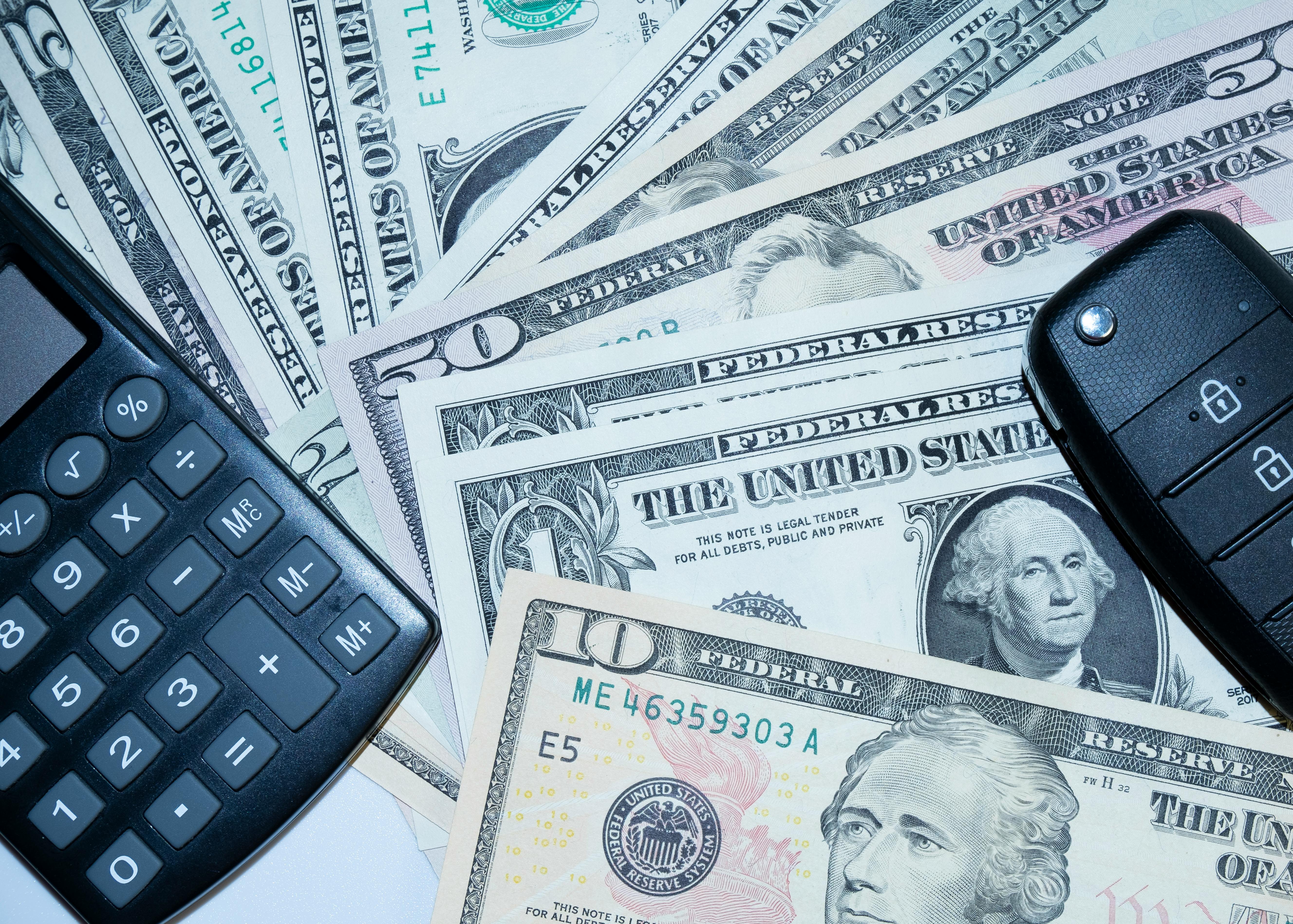 A spread of U.S. dollar bills is shown alongside a calculator | Source: Pexels