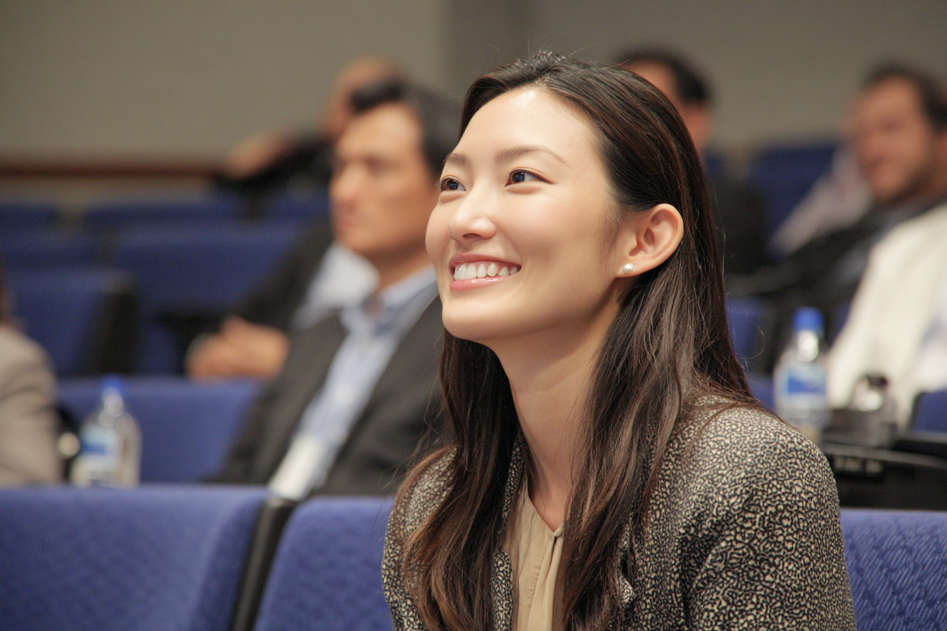 A woman in an auditorium smiling | Source: No source