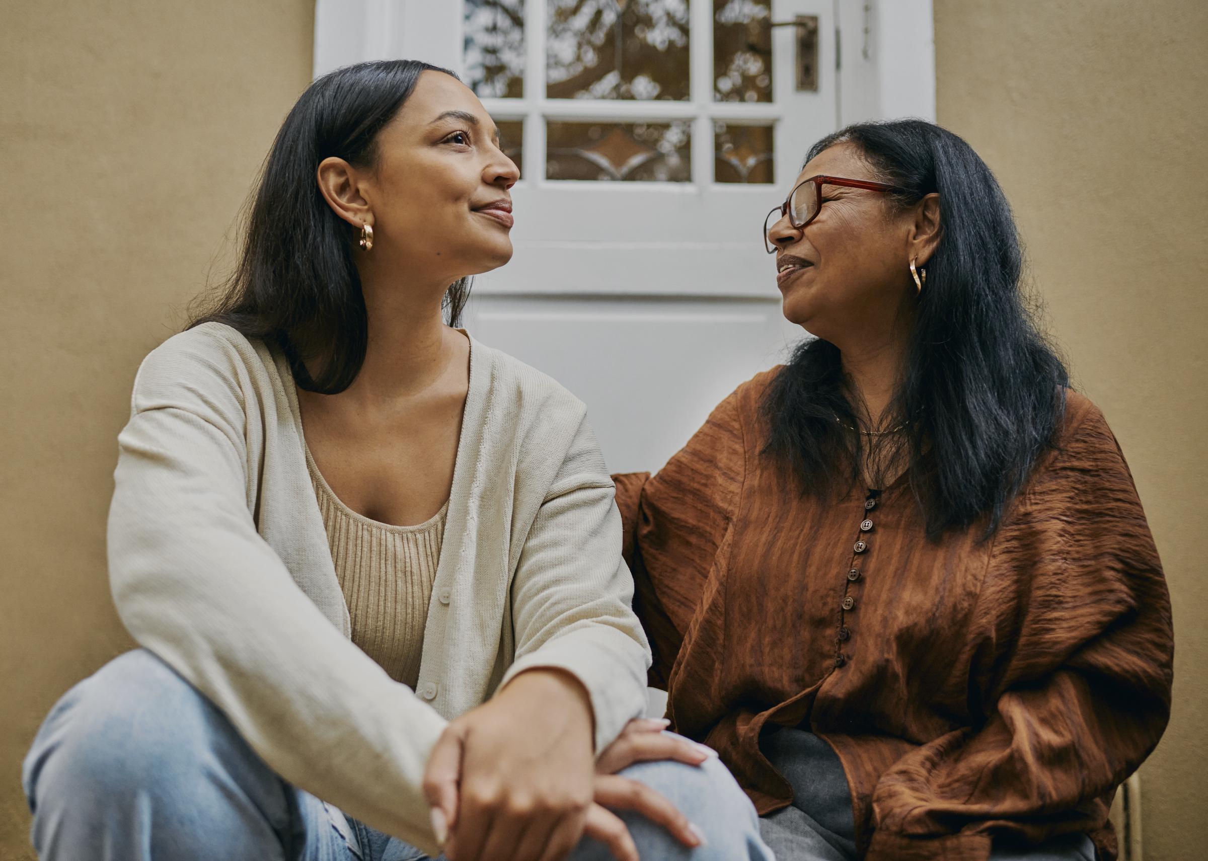 A mother and a daughter sitting on a stoop | Source: Getty Images