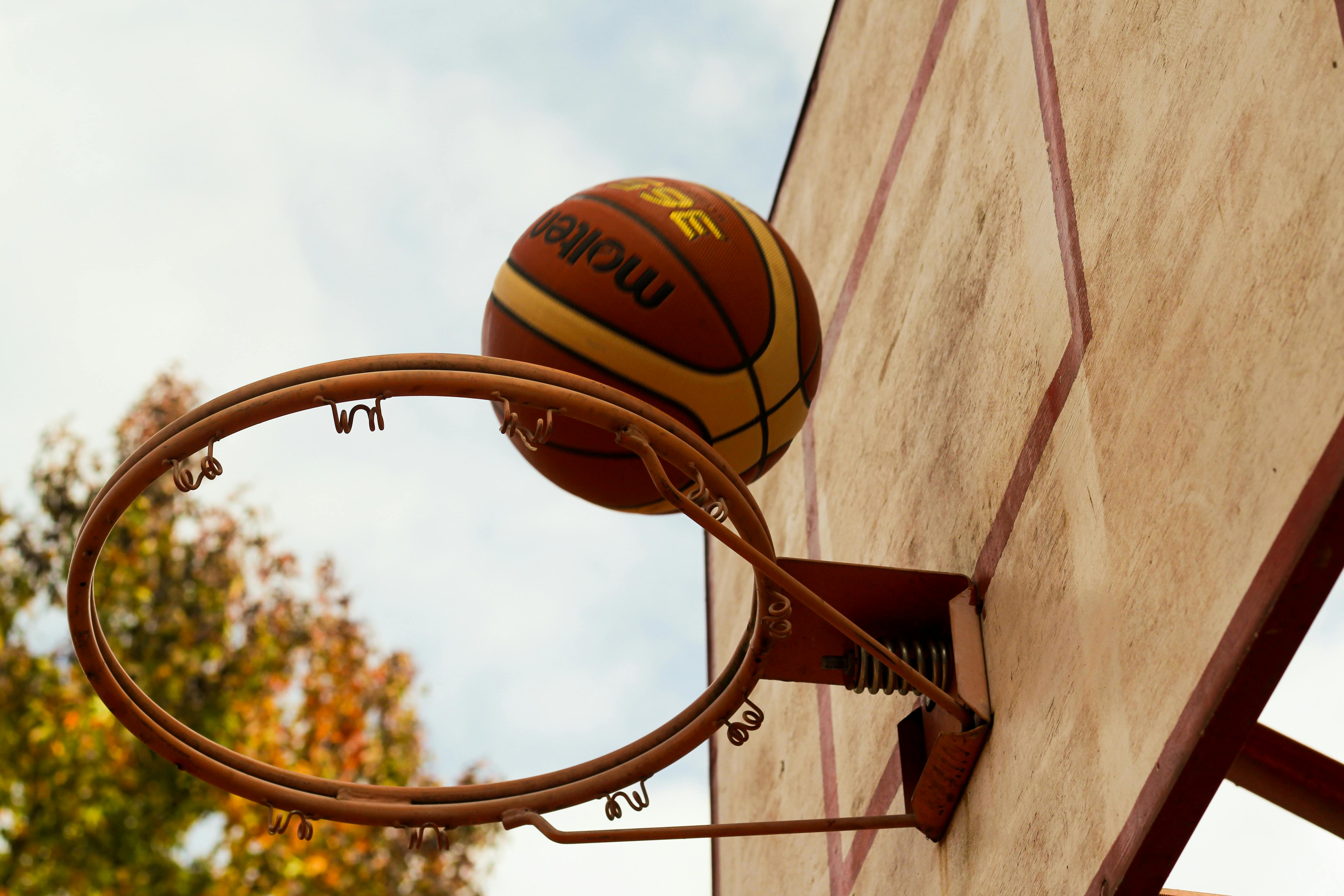 Brown basketball above a steel basketball hoop | Source: Pexels