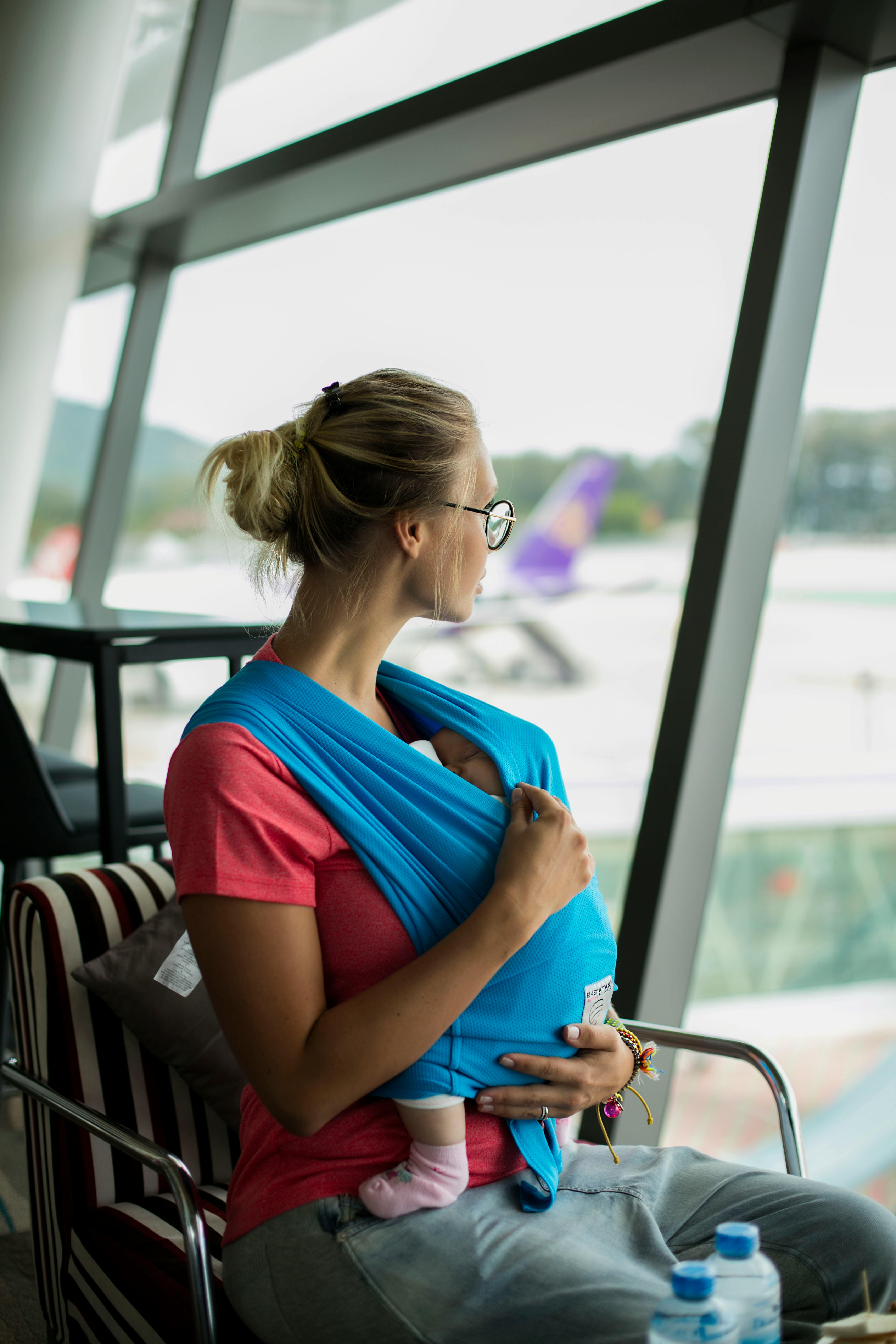 Blonde woman with a baby looking through the window of an airport | Source: Pexels