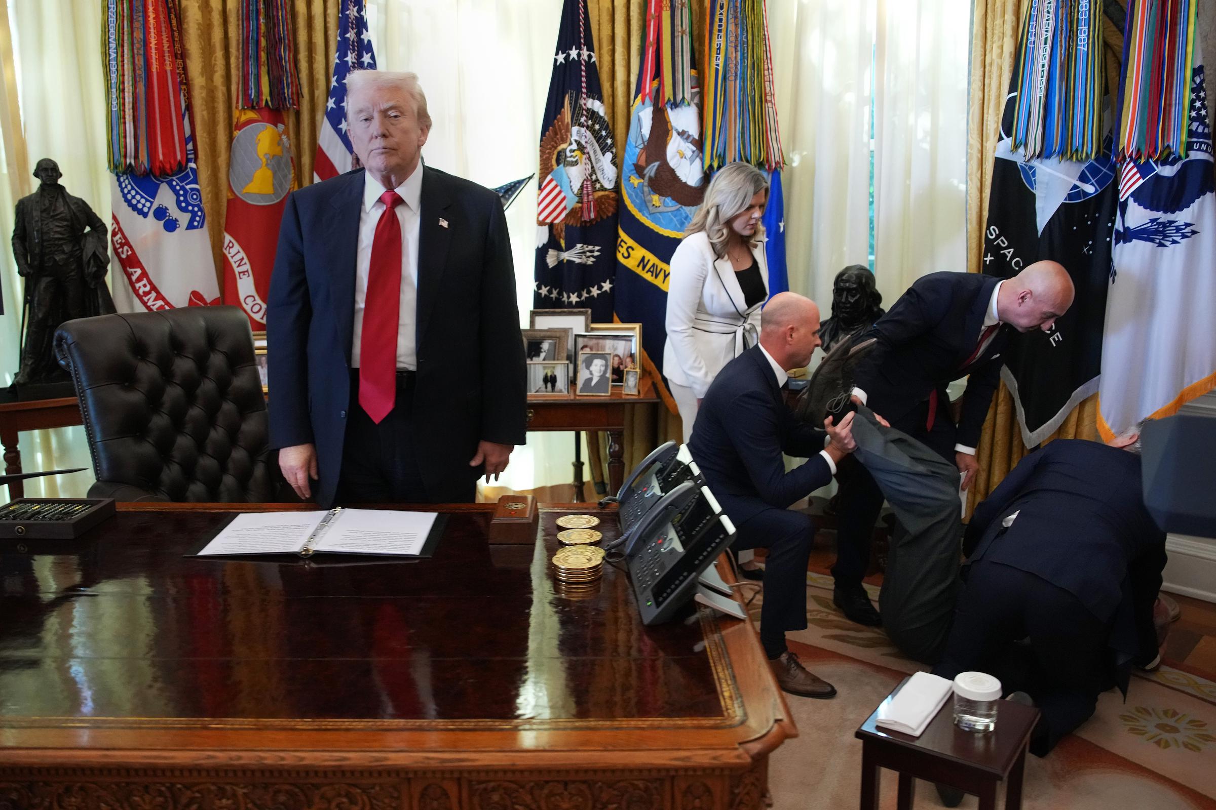 President Donald Trump stands by as attendees help a guest after he collapsed during an event on lowering drug prices in the Oval Office at the White House on November 6, 2025, in Washington, DC | Source: Getty Images