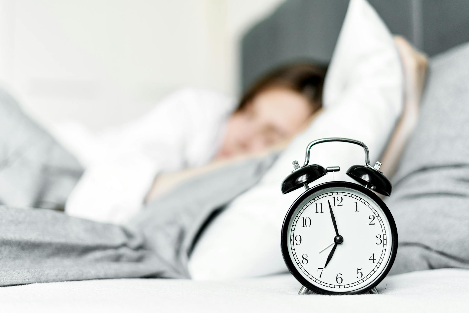 An alarm clock near a sleeping woman | Source: Pexels