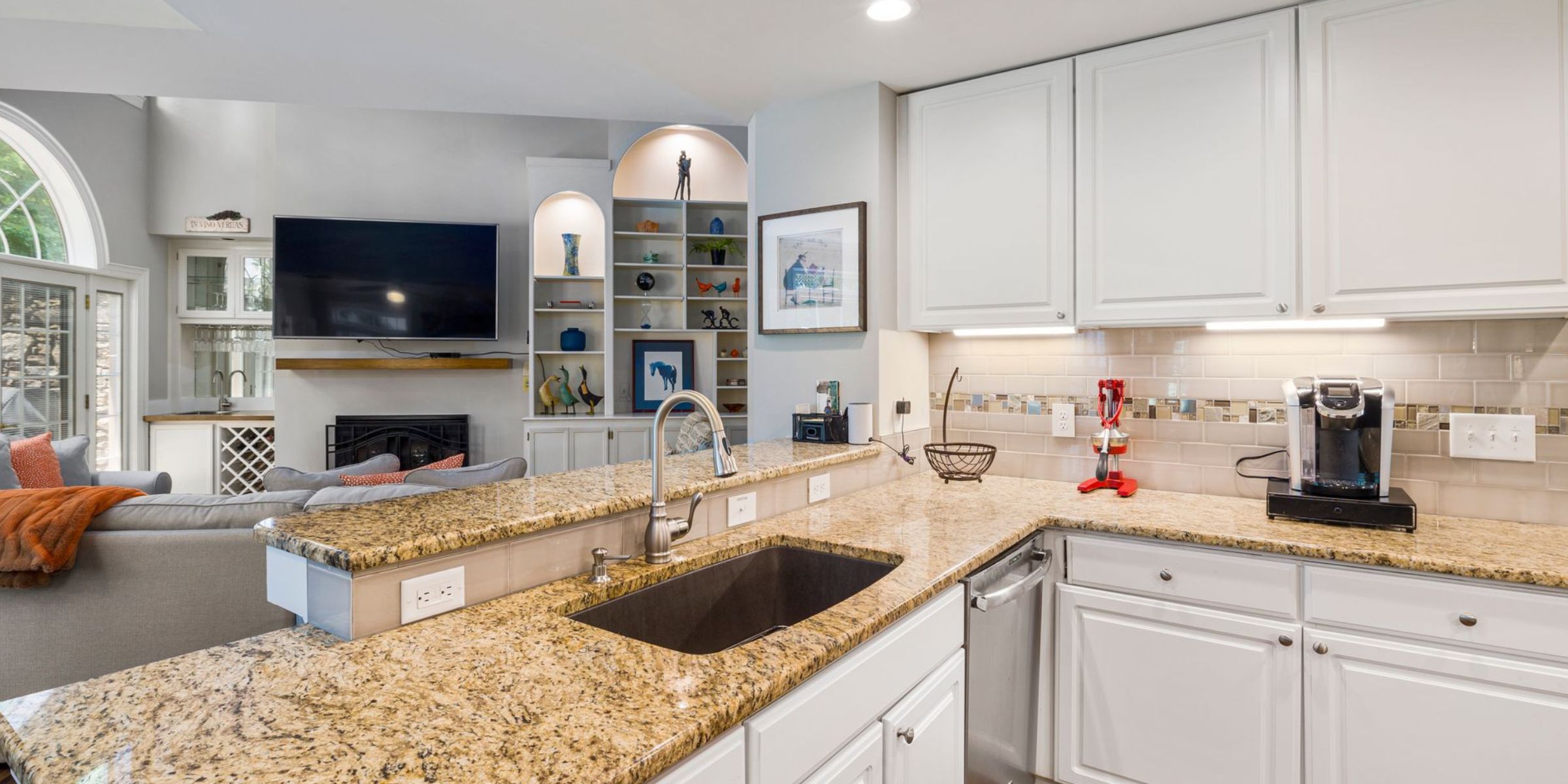 A modern kitchen with granite countertops opens into a stylish living room | Source: Pexels