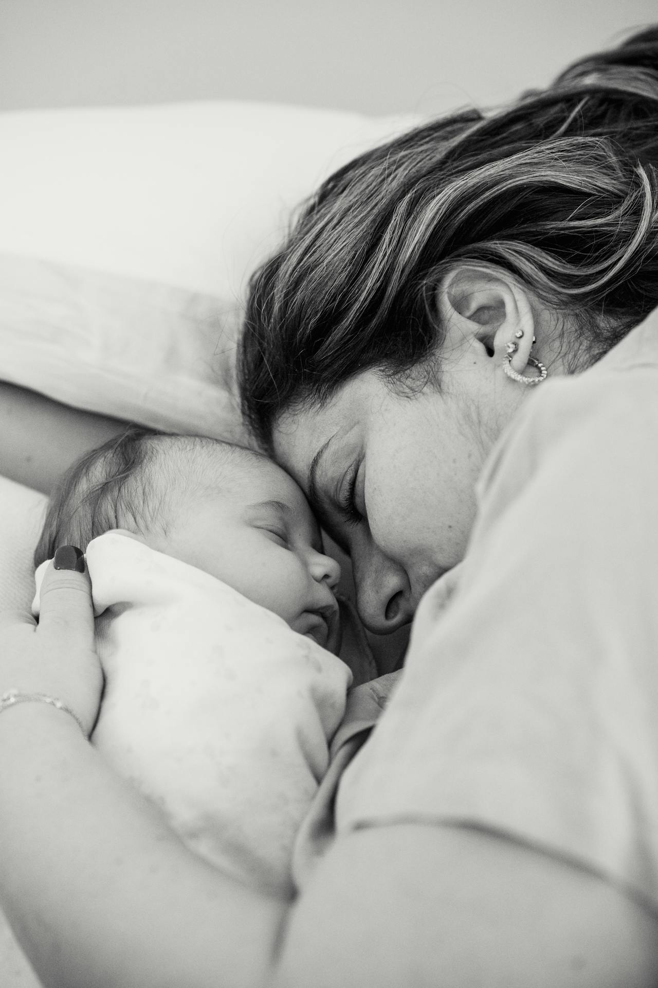Grayscale shot of a woman lying beside her baby | Source: Pexels