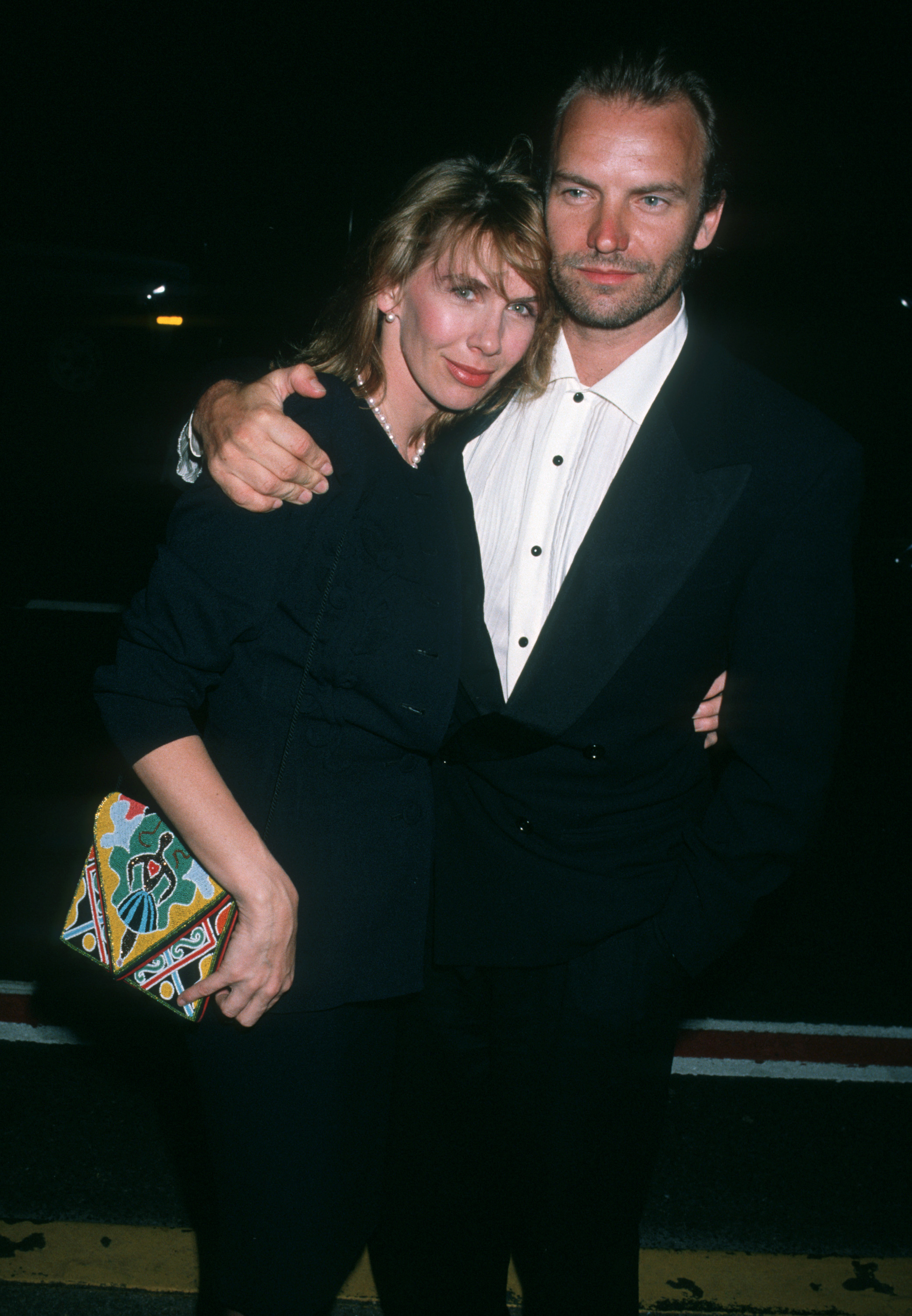 Trudie Styler wears a simple black outfit accessorized with a pearl necklace and a colorful clutch, while seen alongside Sting at the 5th Annual Rock and Roll Hall of Fame Induction Ceremony at the Waldorf Astoria in New York in 1990.