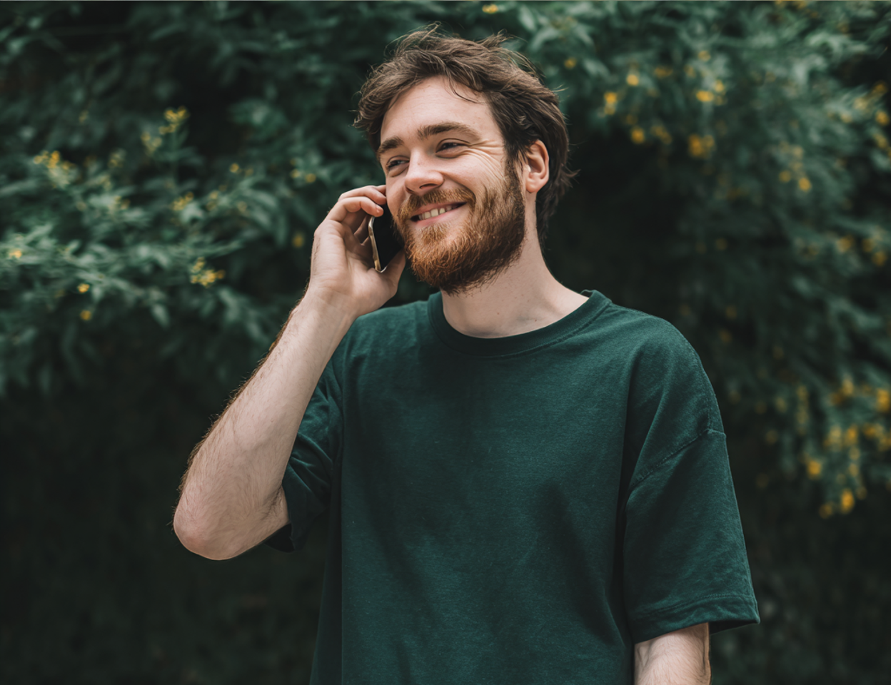 A smiling man talking on a phone | Source: no source