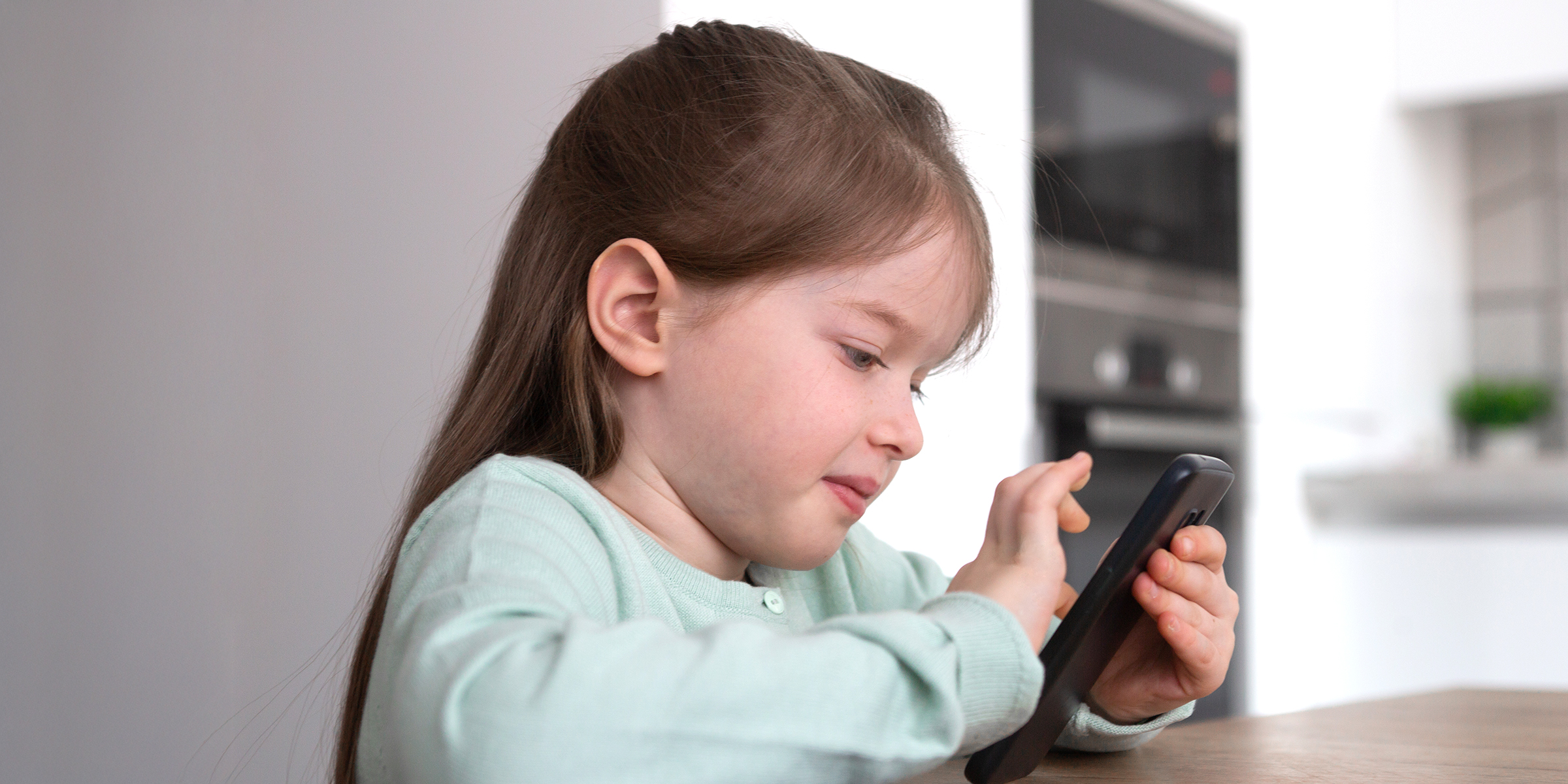 A young girl tapping on her phone | Source: Shutterstock