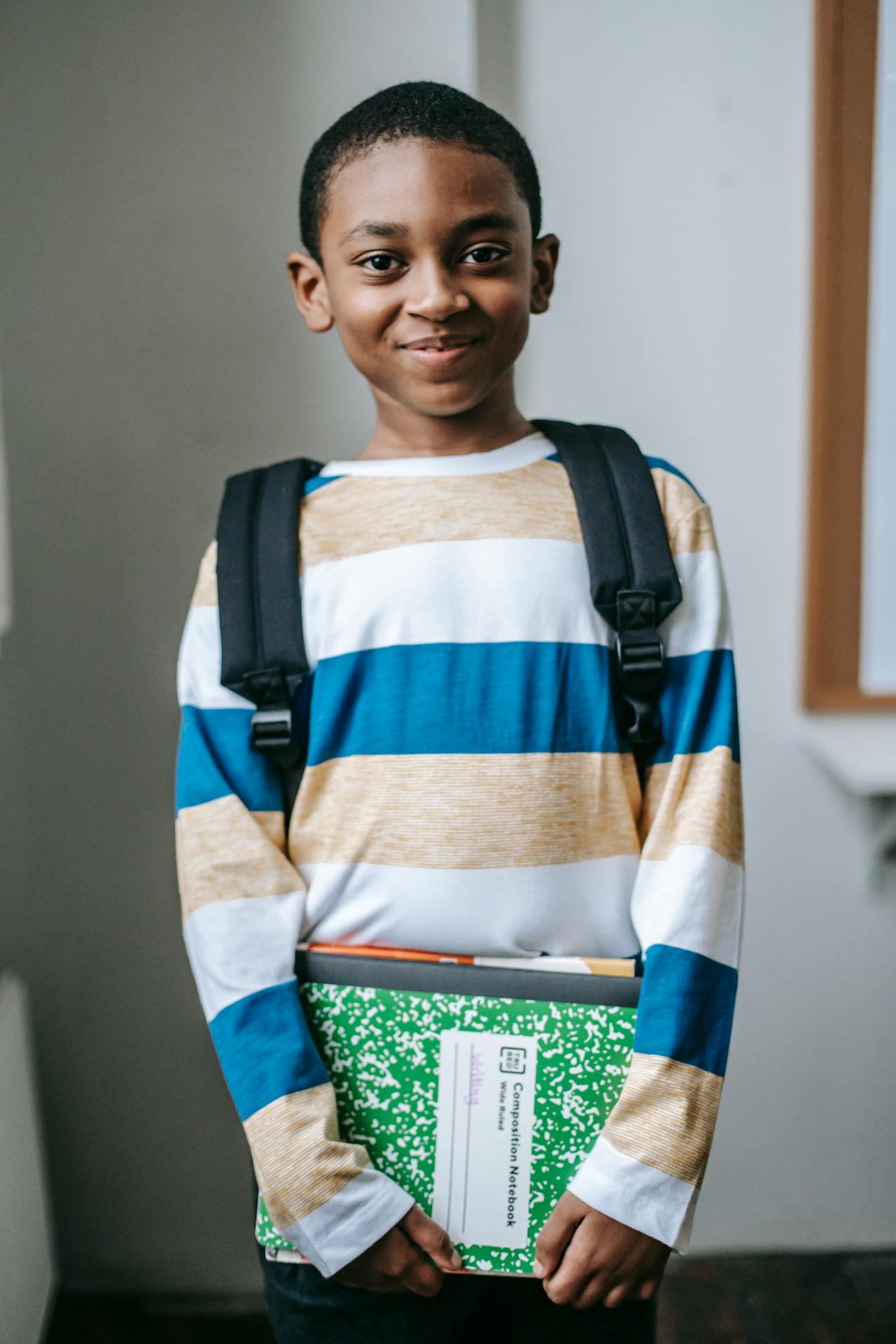 A smiling schoolboy holding his books | Source: Pexels
