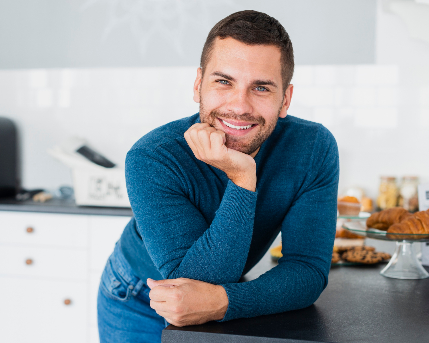 A man leaning on the kitchen counter and smiling | Source: Freepik