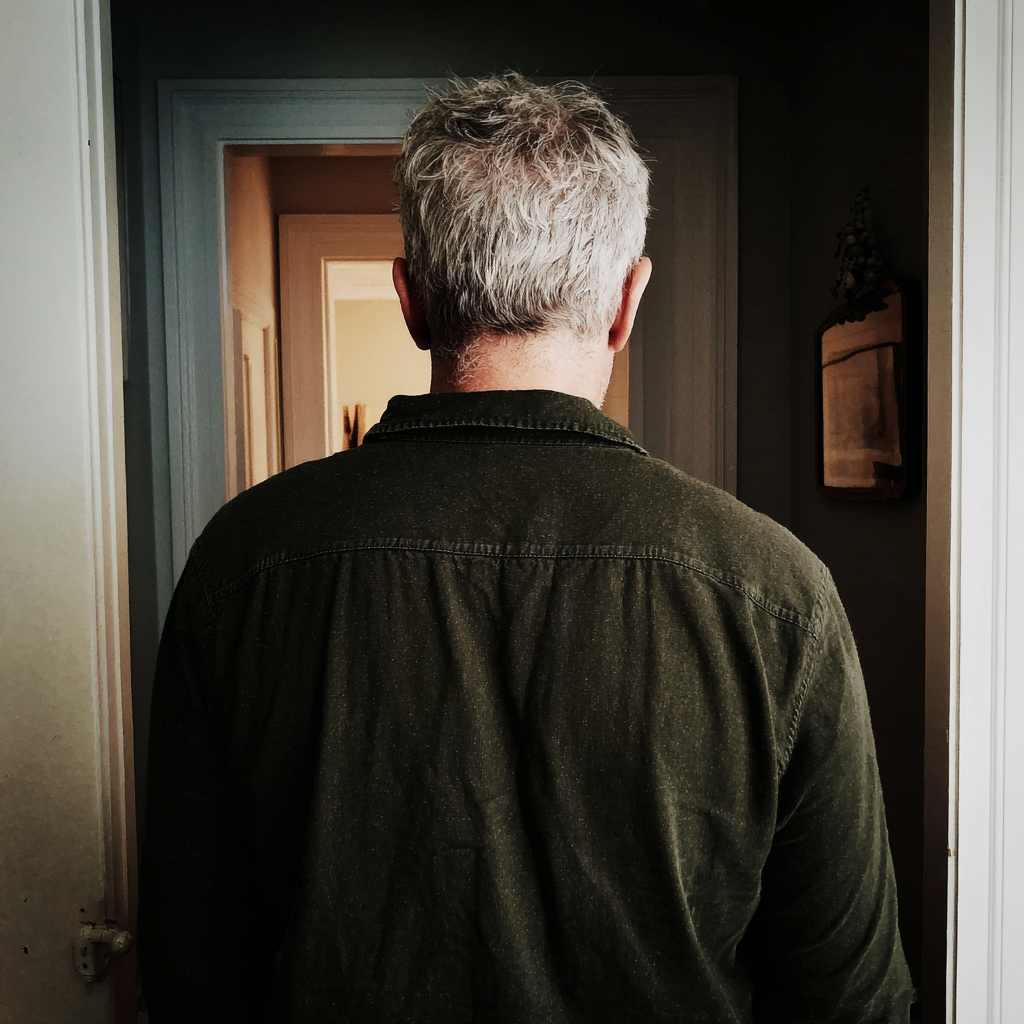 The rear view of an older man standing in a home hallway | Source: no source
