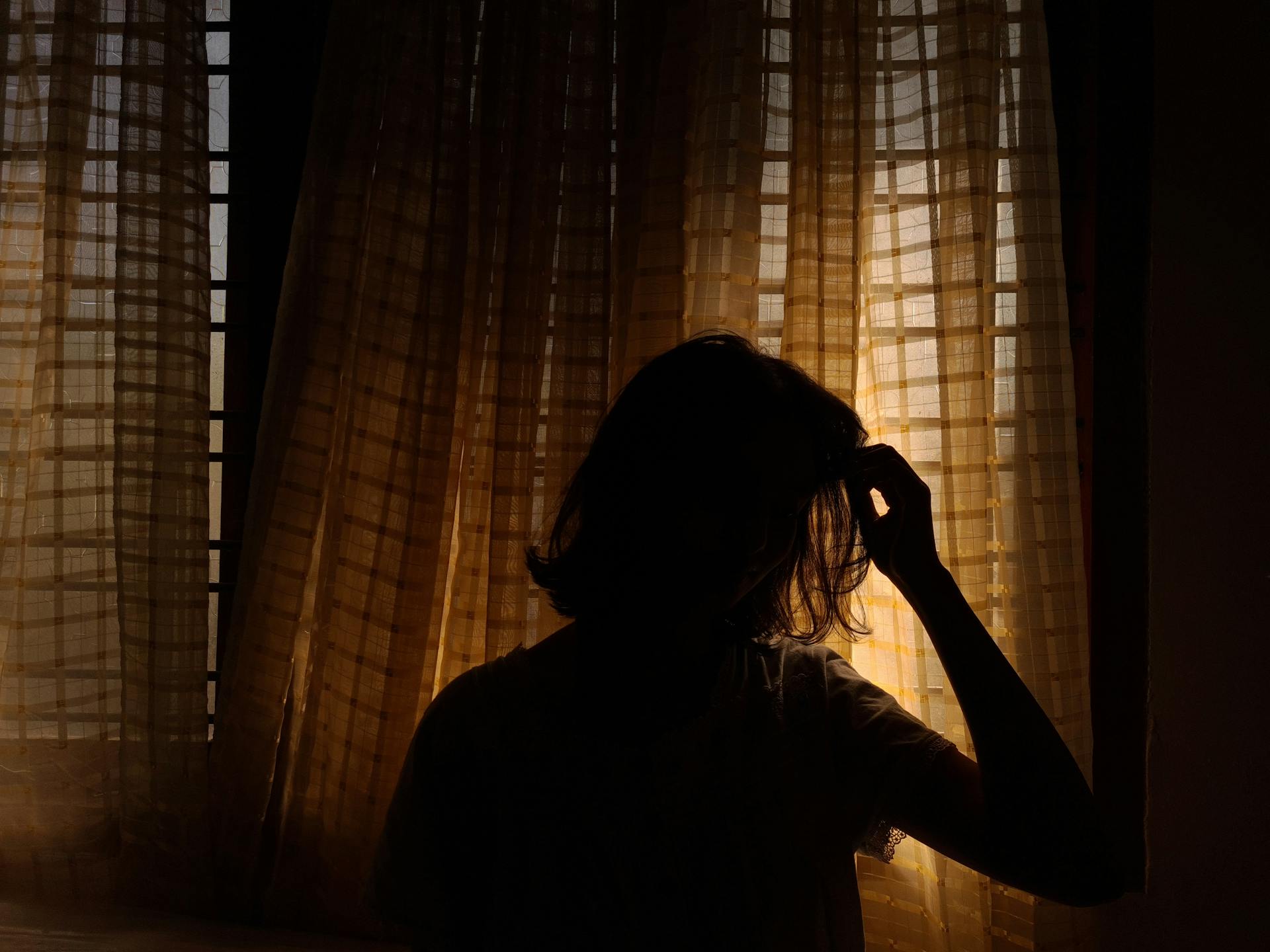 A woman standing by the curtains | Source: Pexels