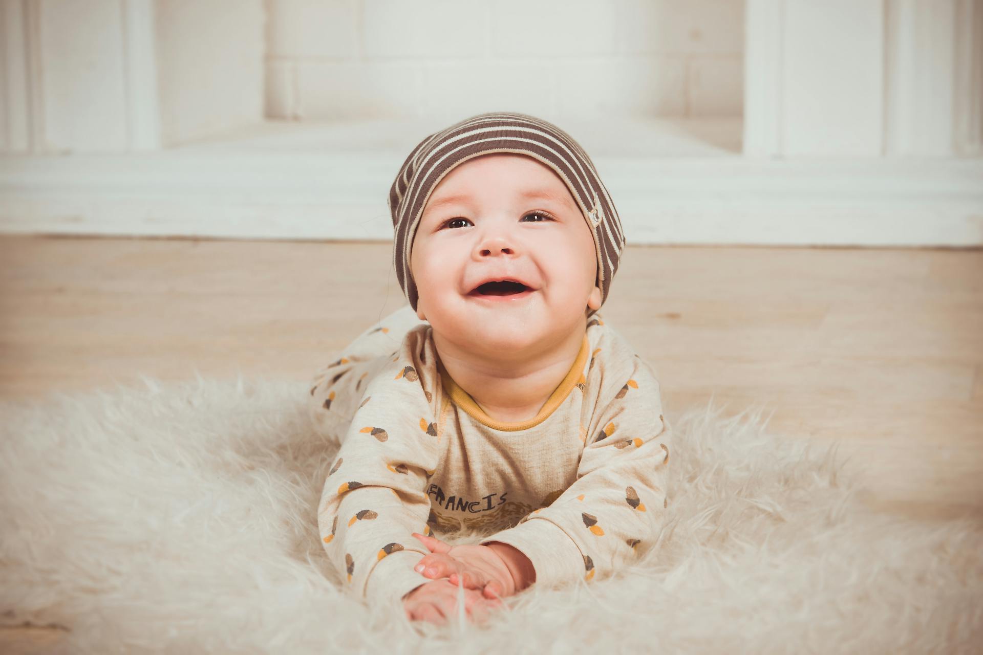 A delighted toddler lying on a fur mat | Source: Pexels