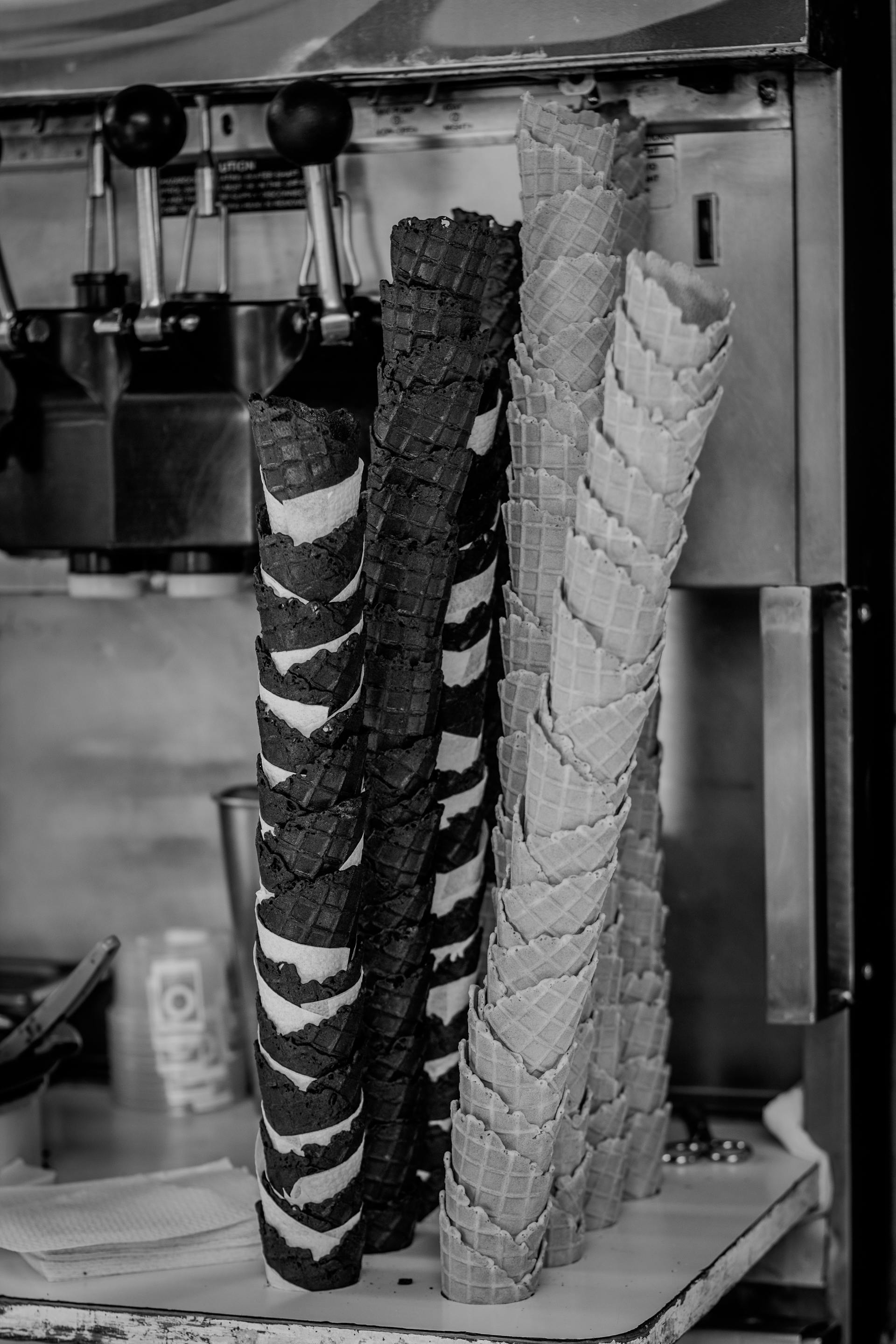 Ice cream cones stacked near an ice cream machine | Source: Pexels