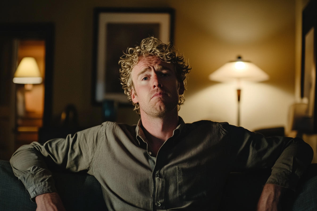 Man in his early 40s sitting back on a couch with pursed lips and an unapologetic expression | Source: no source