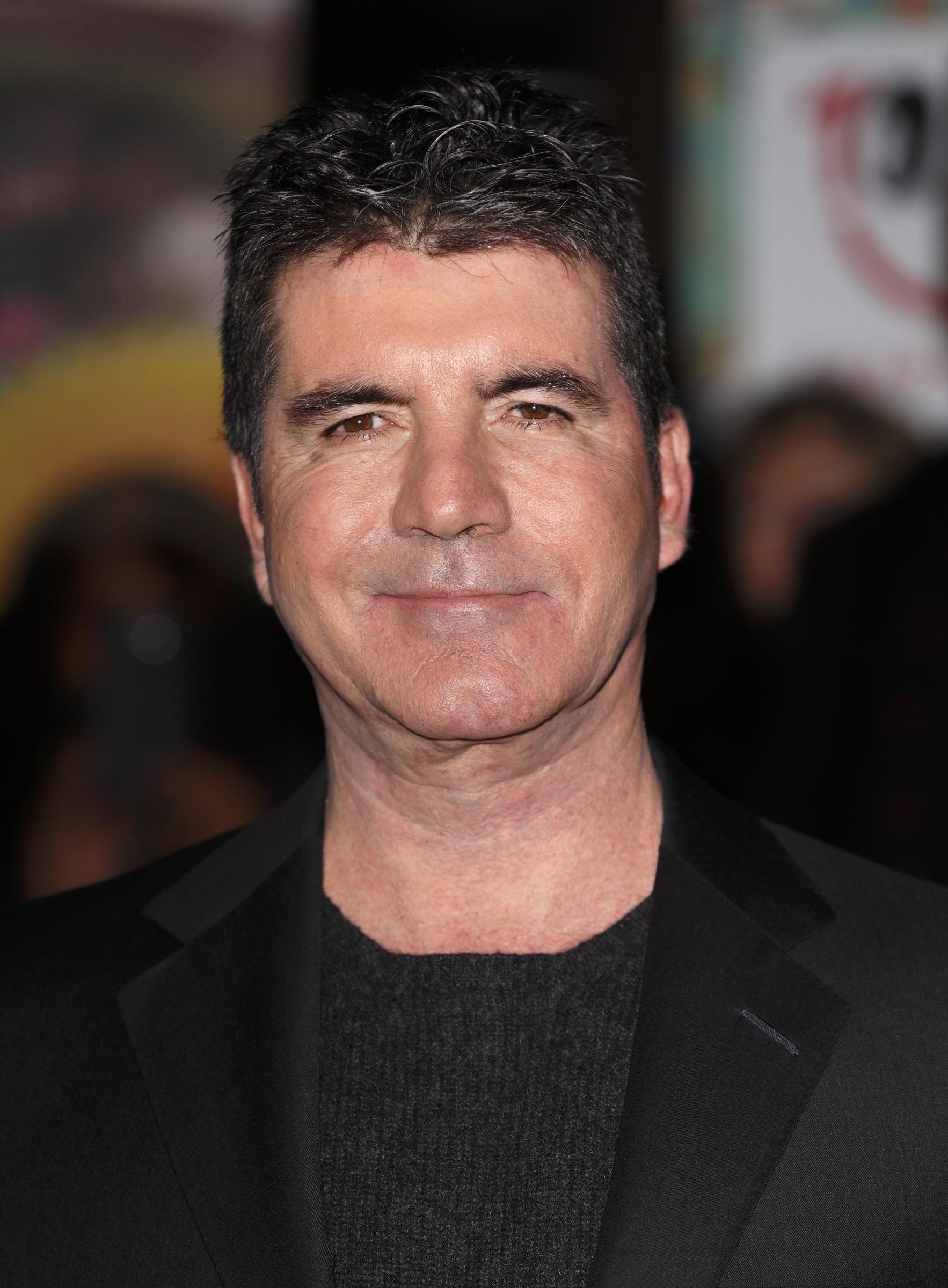 Fast forward to 2014, and Cowell steps onto the ICAP Charity Day floor in London with a pared-down look — no tie, just confidence. The understated blazer and crew neck mark a new era of laid-back authority.