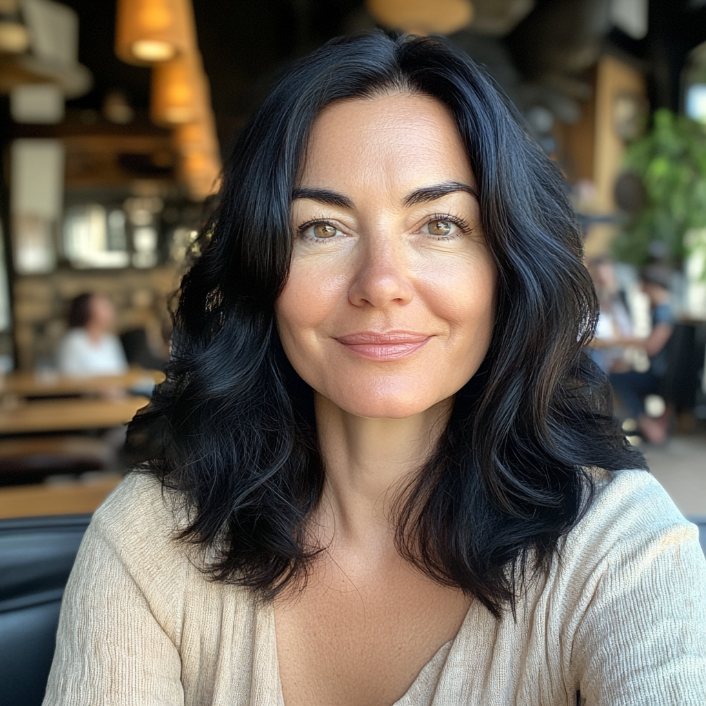 A smiling woman sitting in a coffee shop | Source: No source