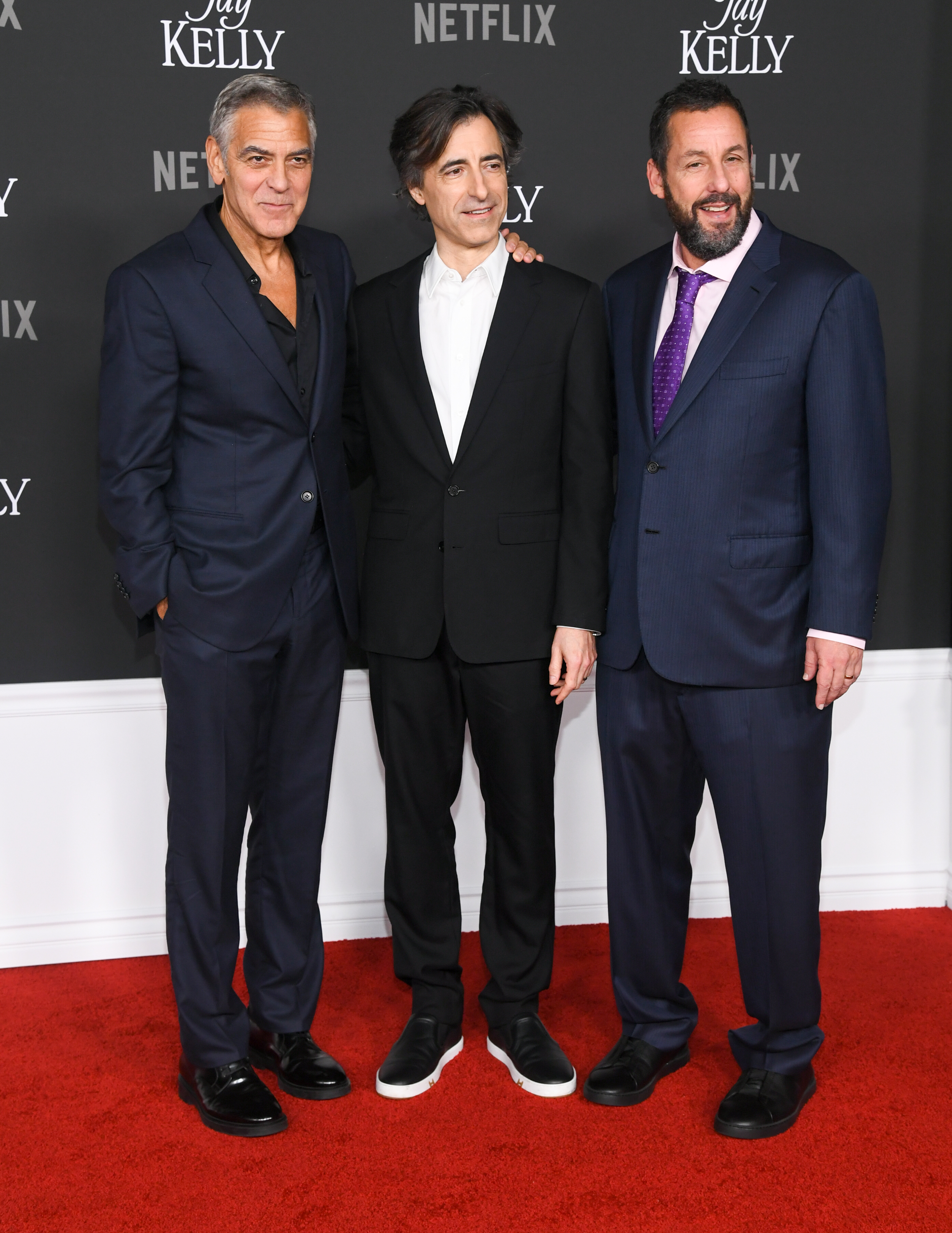 George Clooney, Noah Baumbach, and Adam Sandler, all dressed in sharp suits, showcase their bond at the "Jay Kelly" premiere. Looking handsome and united, they exude a strong sense of brotherhood.