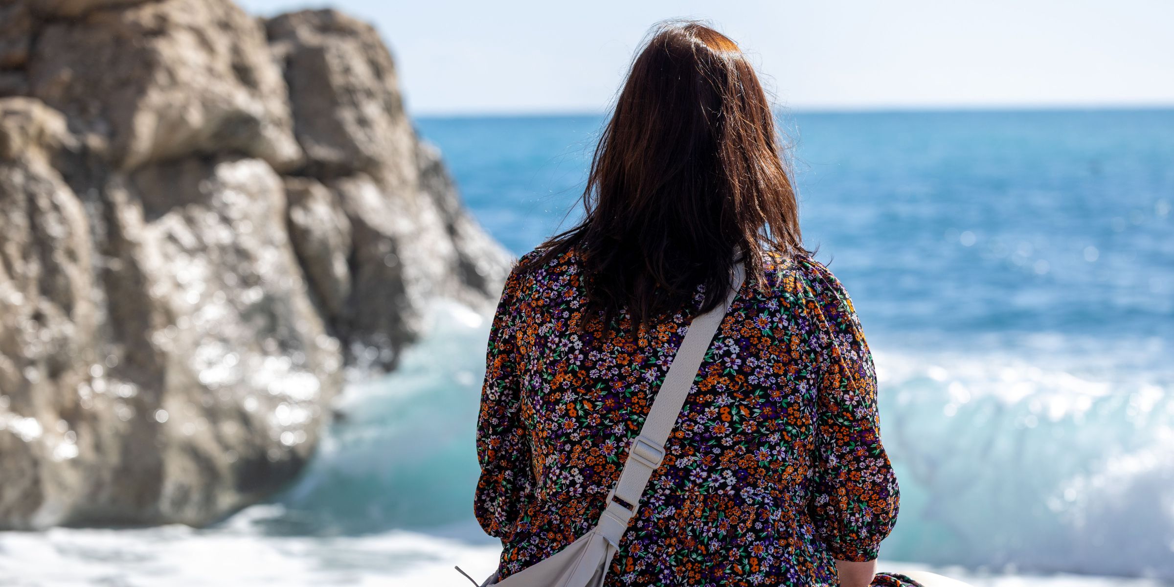 The back view of a woman sitting on a beach looking at the ocean | Source: Pexels