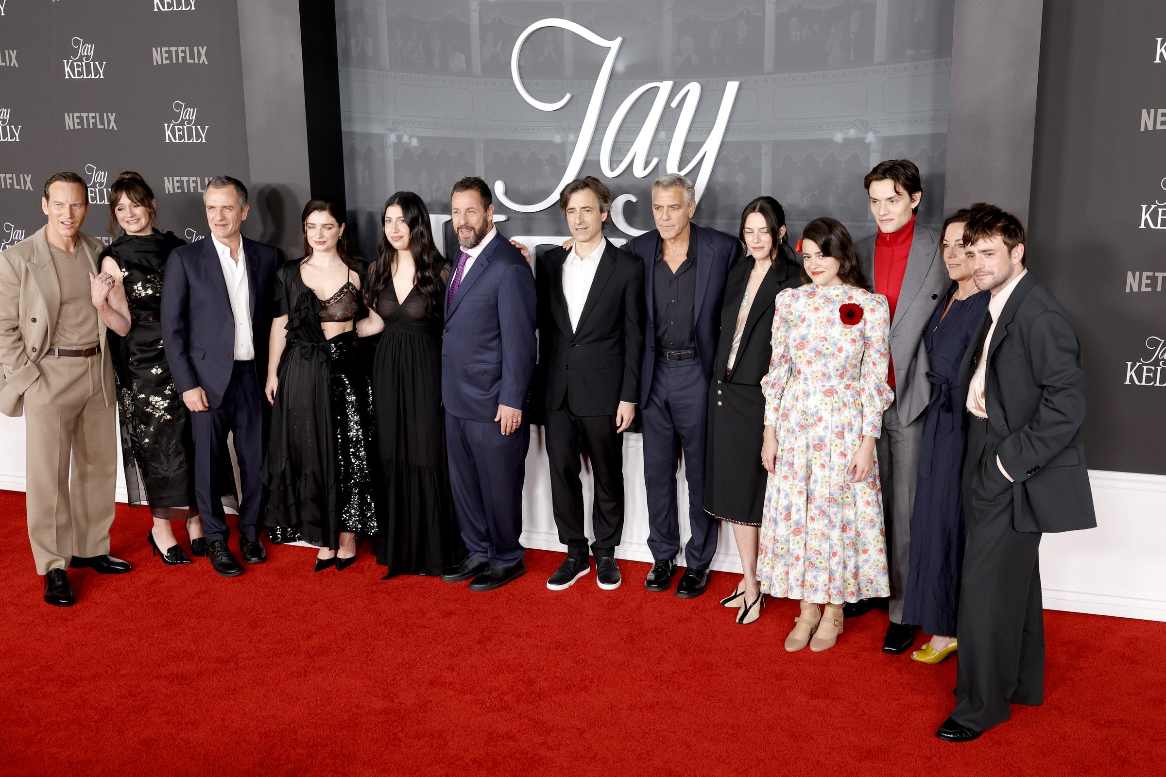 The cast of "Jay Kelly" — including Patrick Wilson, Emily Mortimer, David Heyman, Eve Hewson, Sadie Sandler, Adam Sandler, Noah Baumbach, George Clooney, Riley Keough, Grace Edwards, Louis Partridge, Nina Gold, and Charlie Rowe — gather for a group photo at the film's premiere.