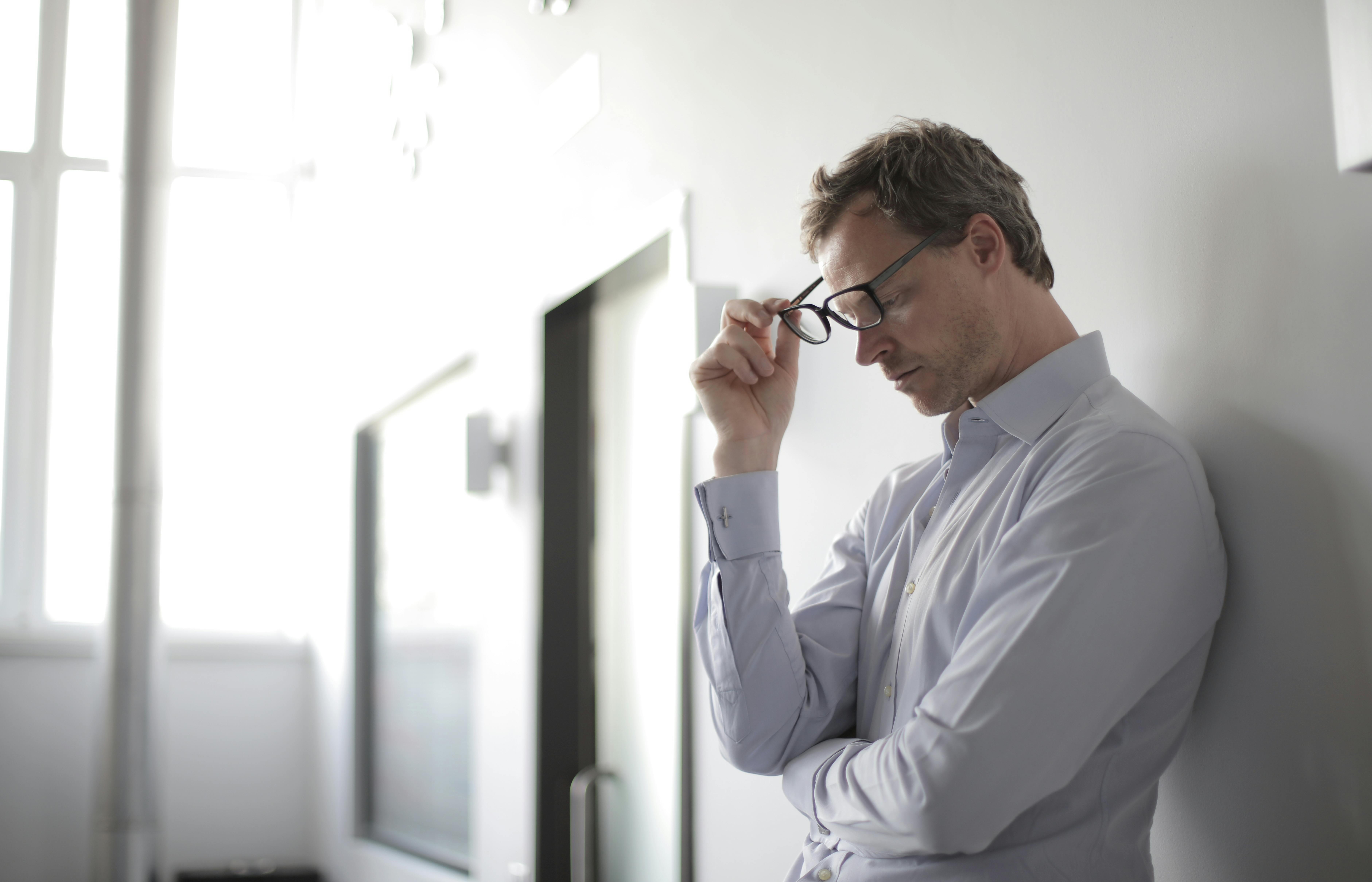 Stressed man holding eye glasses | Source: Pexels