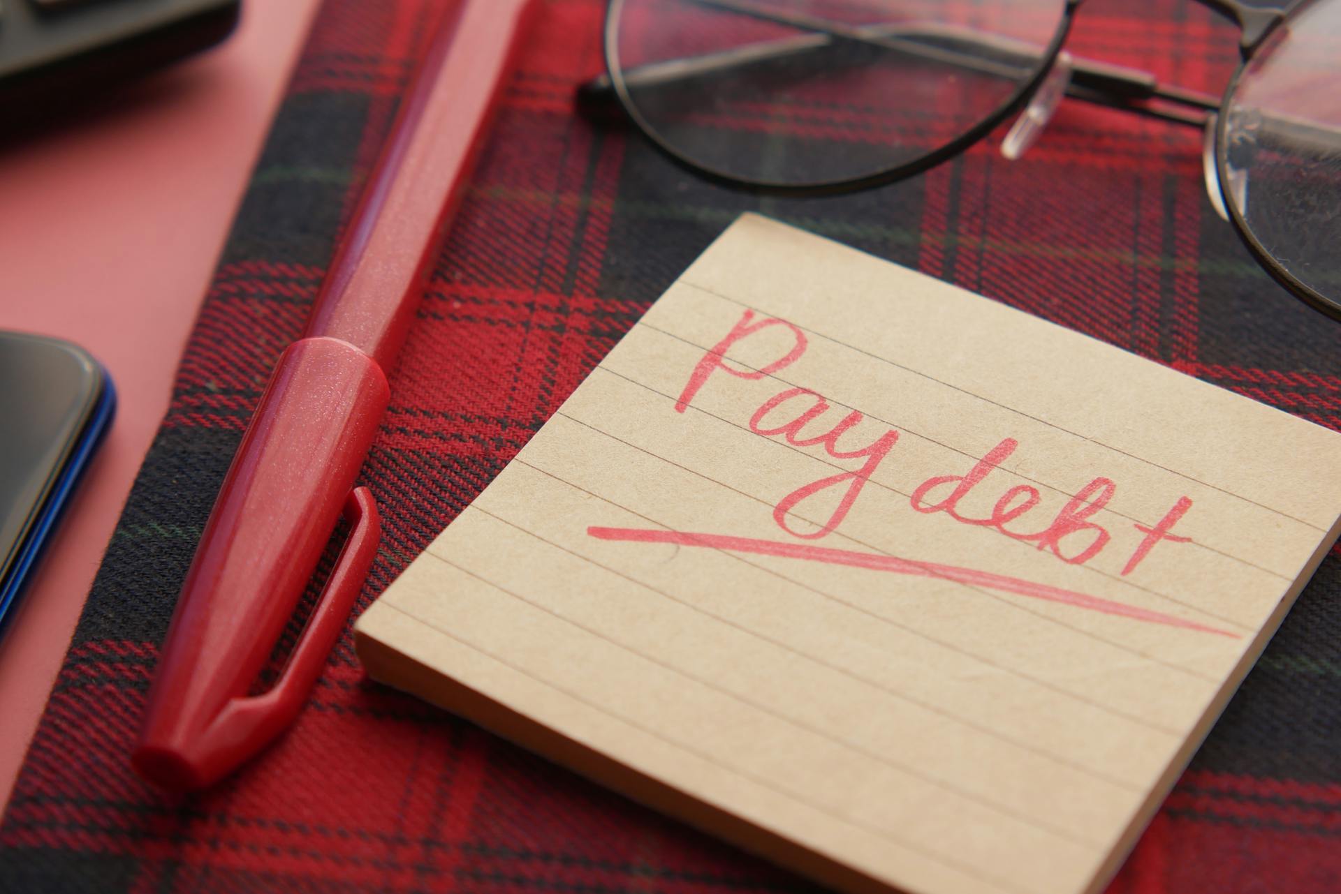 A notebook with "Pay Debt" written on it | Source: Pexels