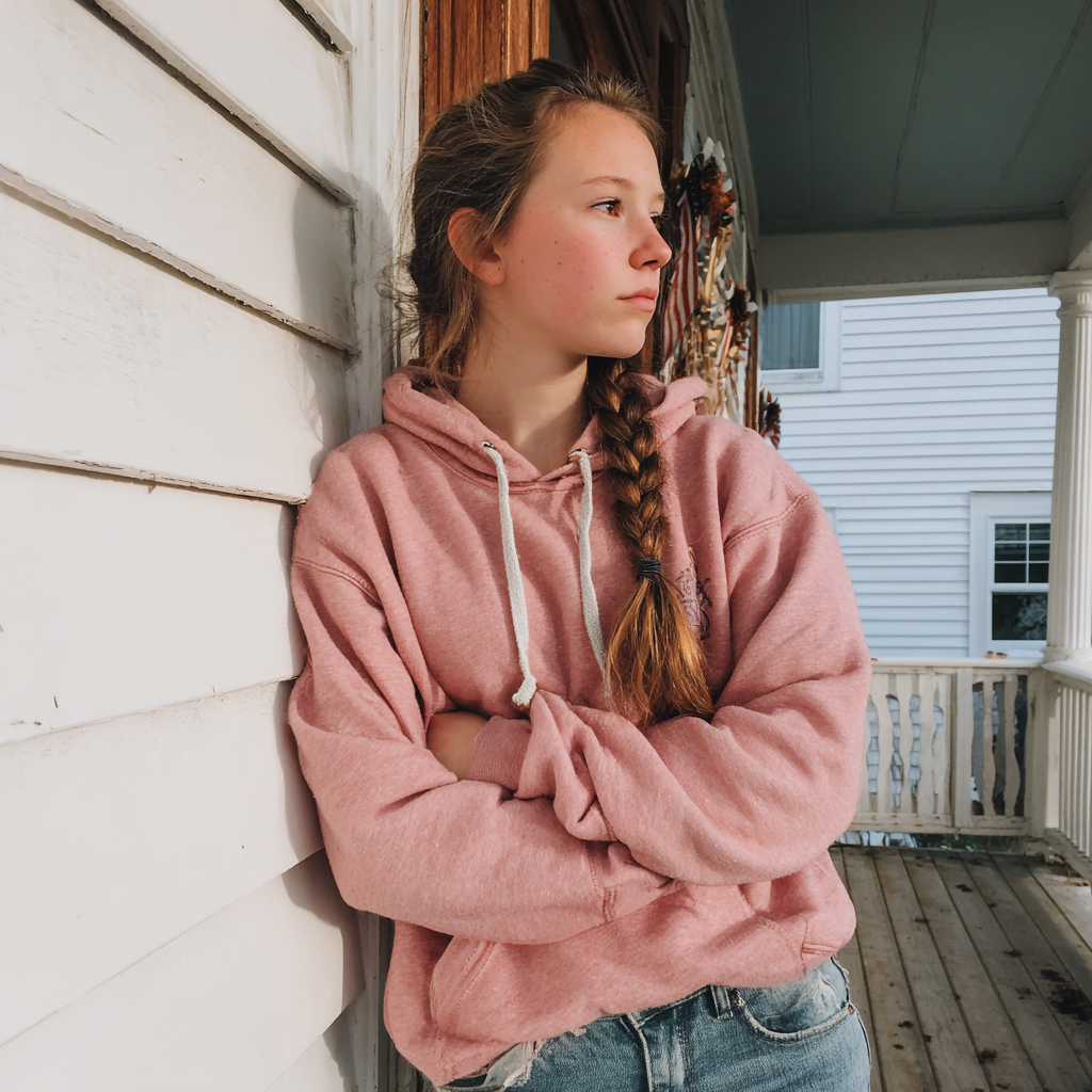 A teenage girl standing on a porch | Source: No source
