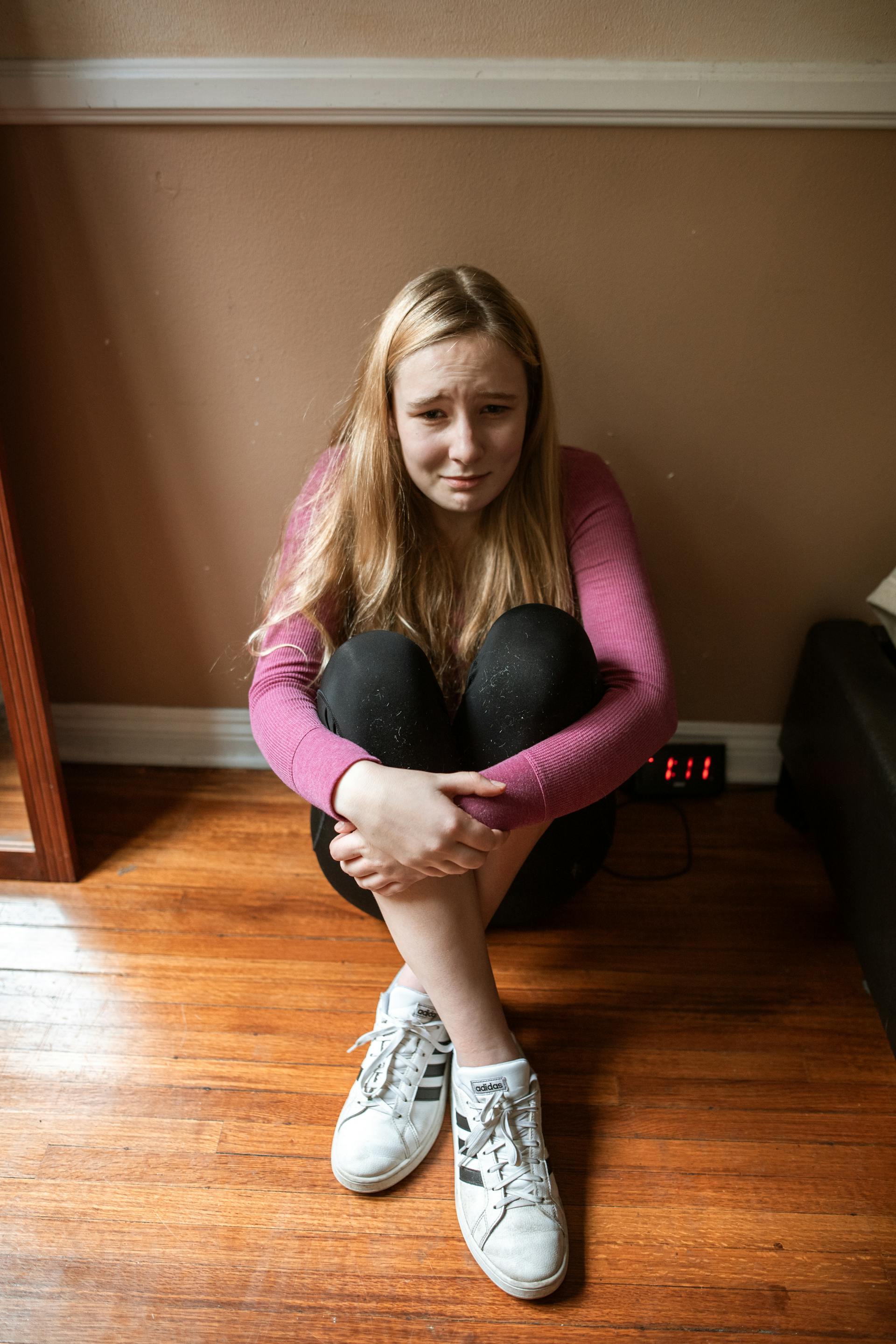 A teenage girl sitting on the floor and crying | Source: Pexels