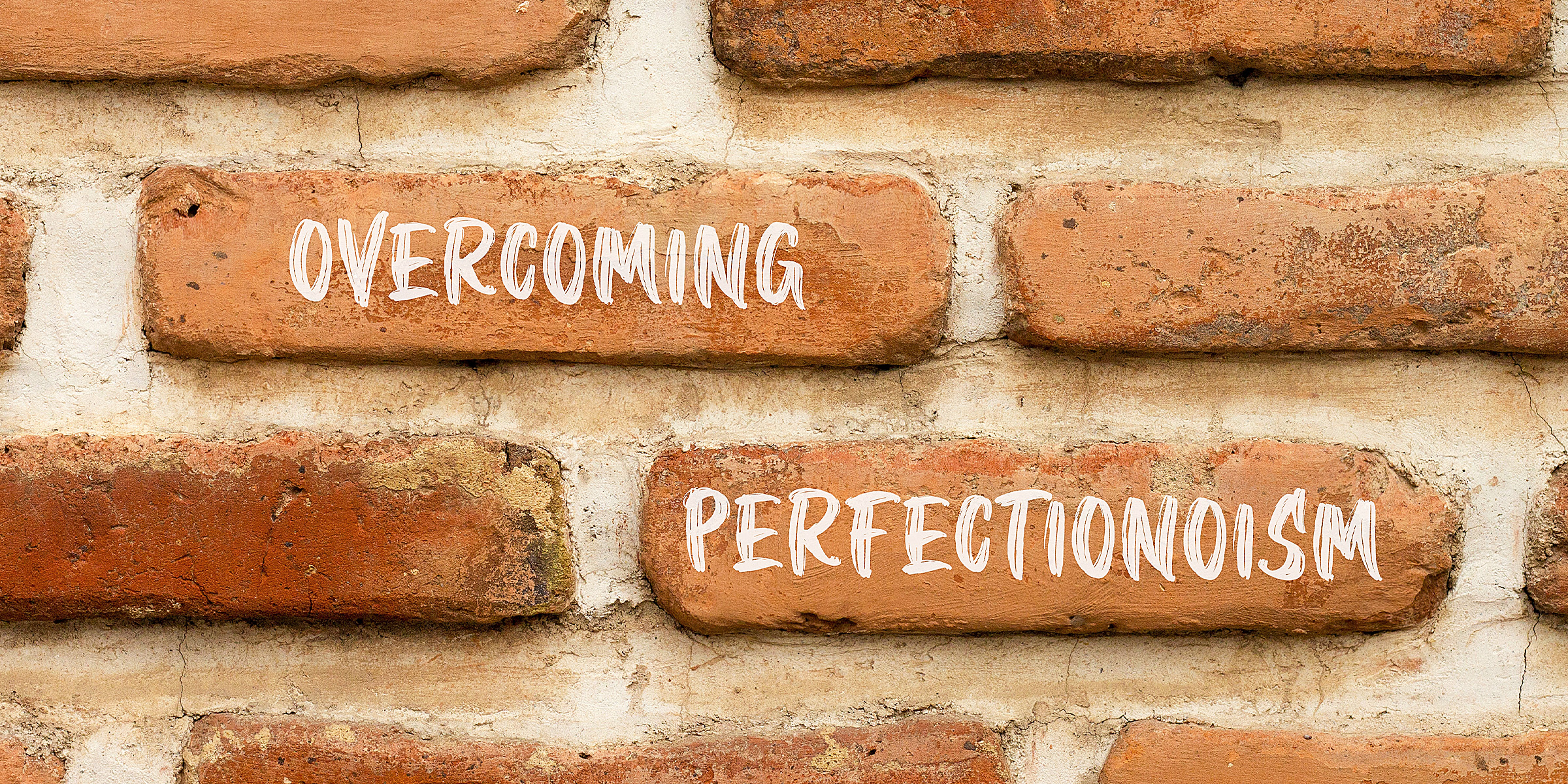 The word overcoming perfectionism on a brick wall | Source: Shutterstock
