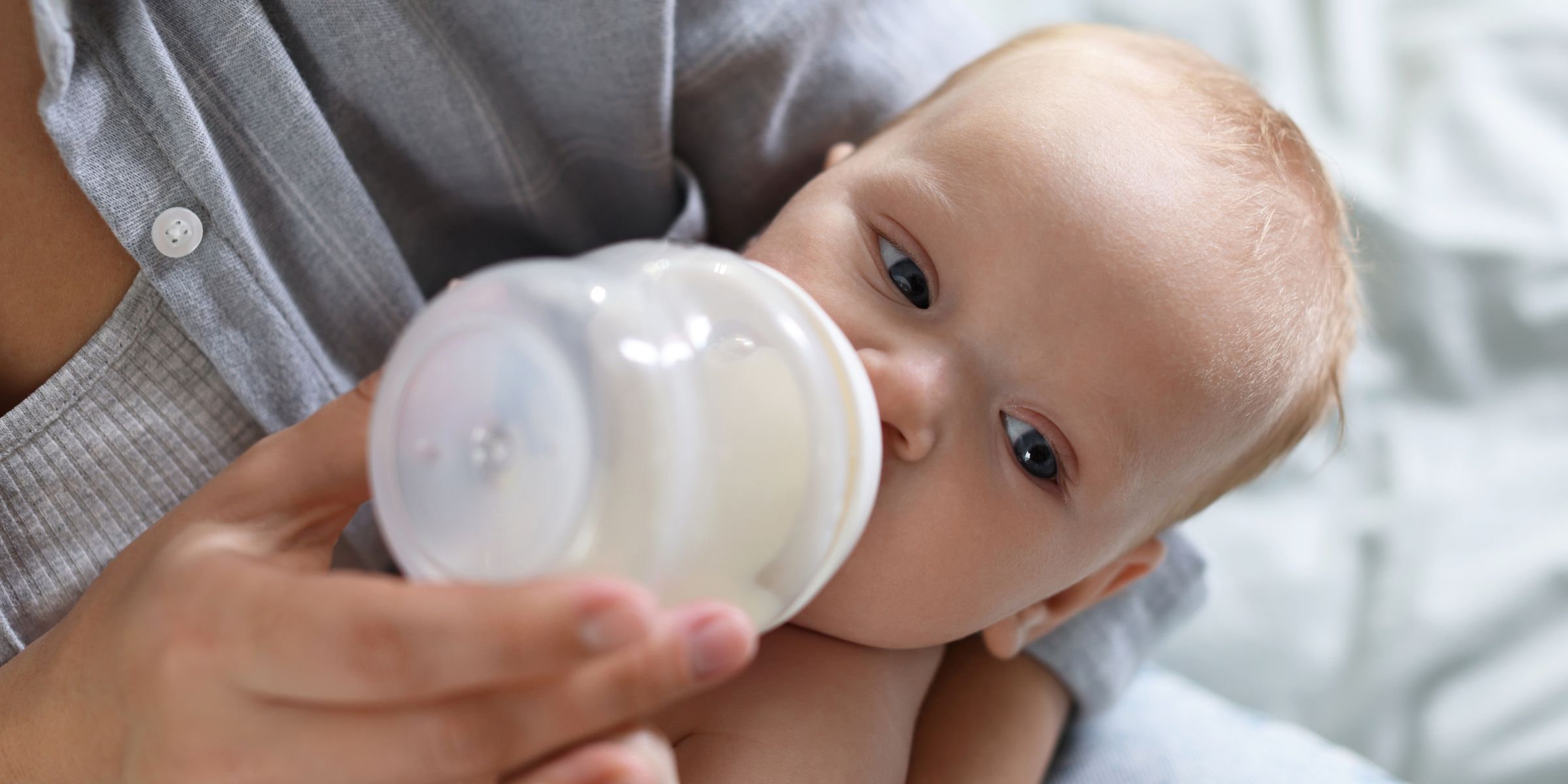 A newborn baby drinking formula while being cradled in a mother's arms | Source: Shutterstock