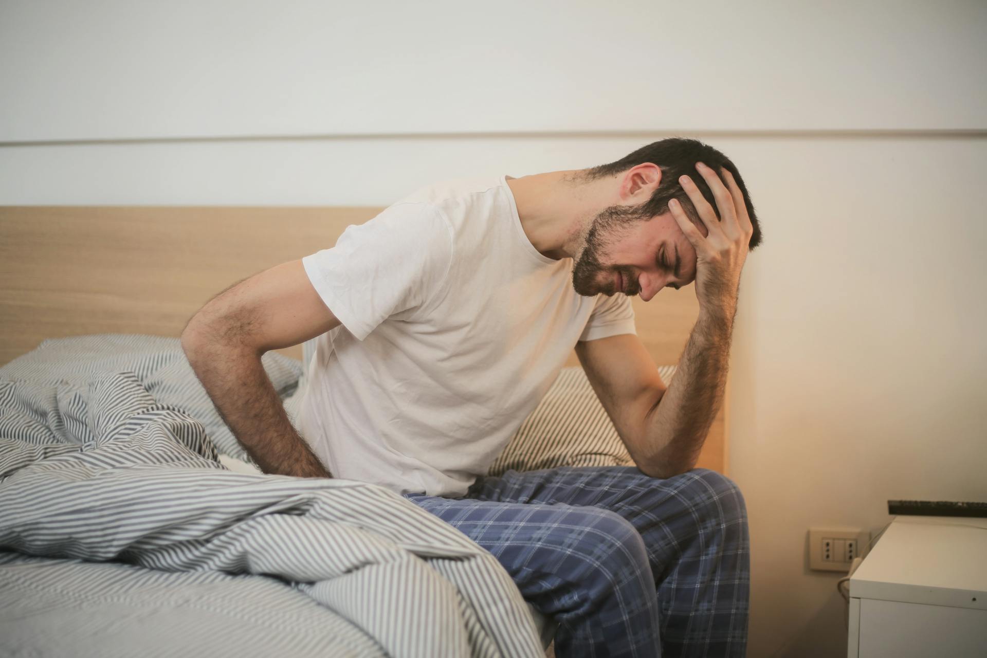 An exhausted man sitting on his bed | Source: Pexels