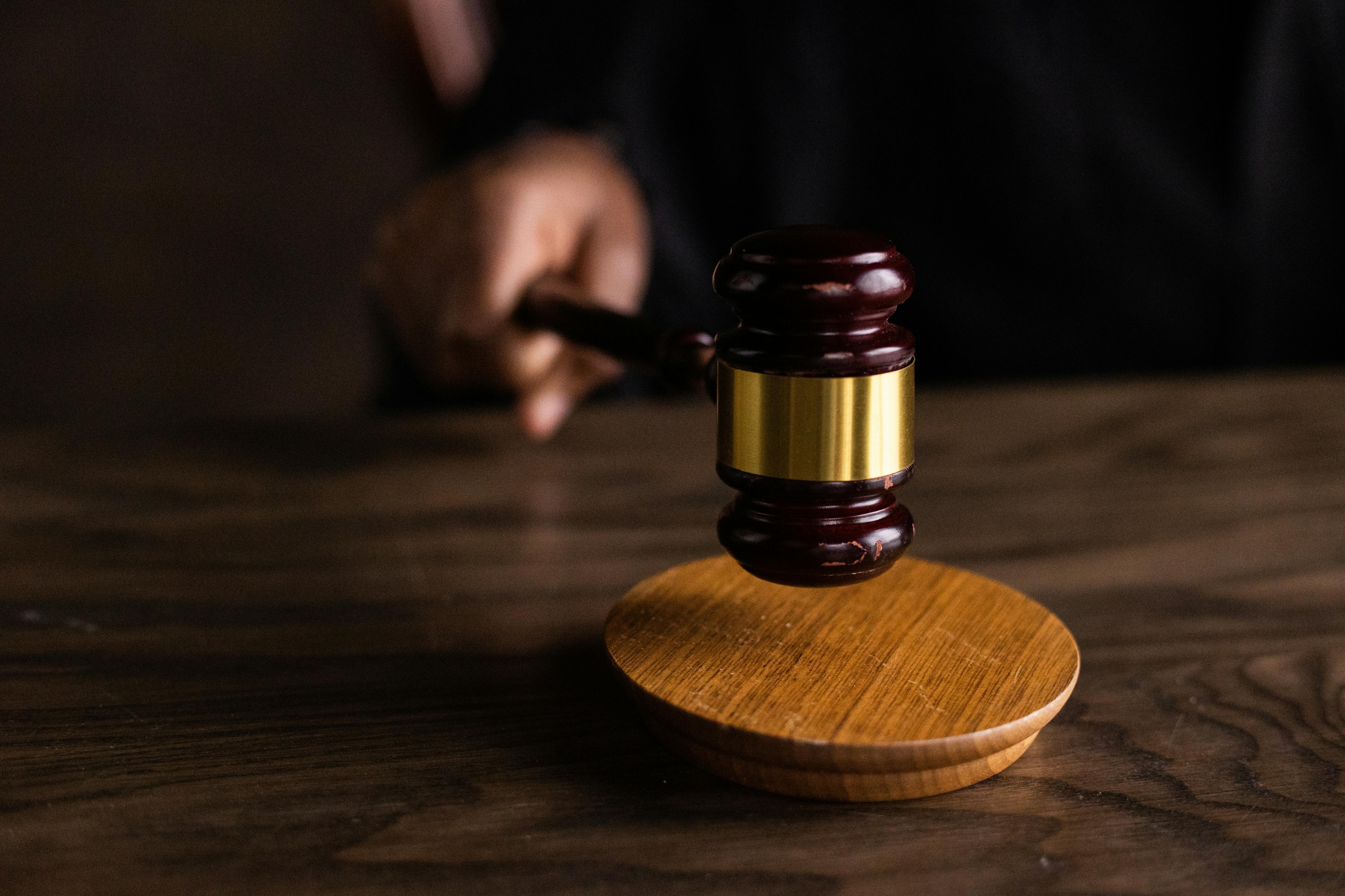 A person holding brown wooden gavel on a brown wooden table | Source: Pexels