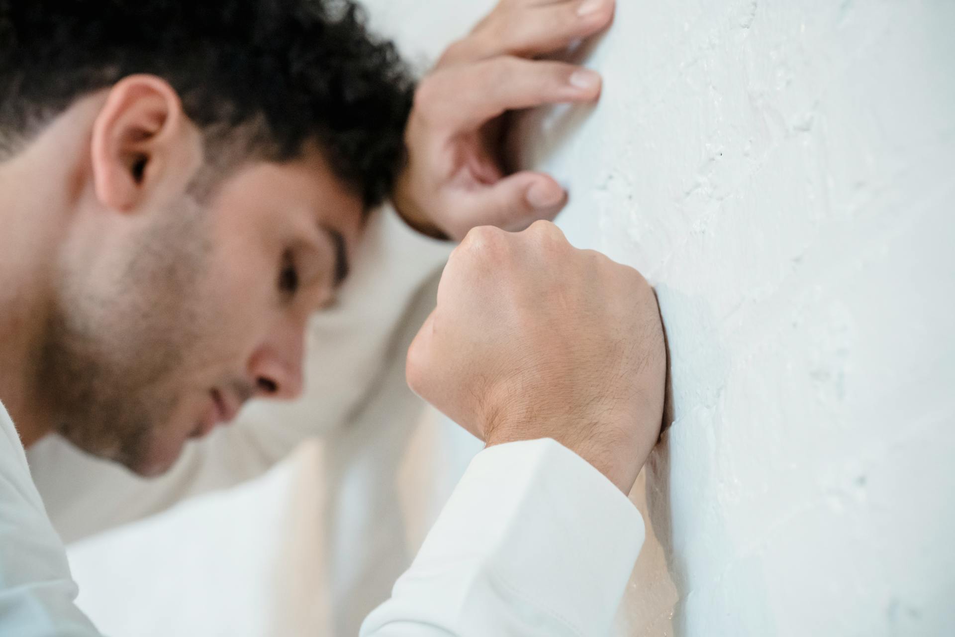 A depressed man leaning his head on the wall | Source: Pexels
