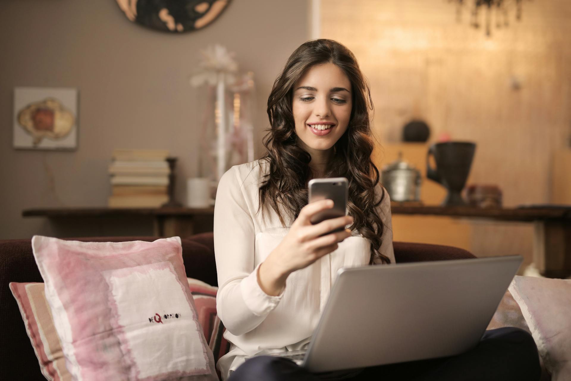 Young woman using her phone in front of a computer | Source: Pexels