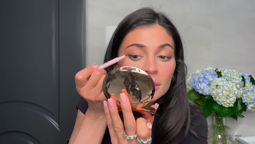 Kylie Jenner doing her classic beauty routine from a video dated April 6, 2023. | Source: YouTube/Vogue