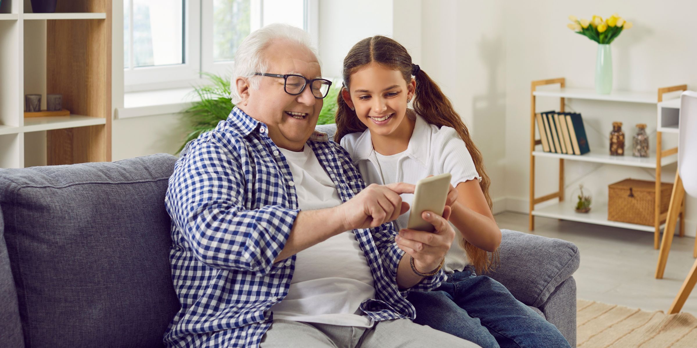 An old man showing his phone to a little girl | Source: Shutterstock