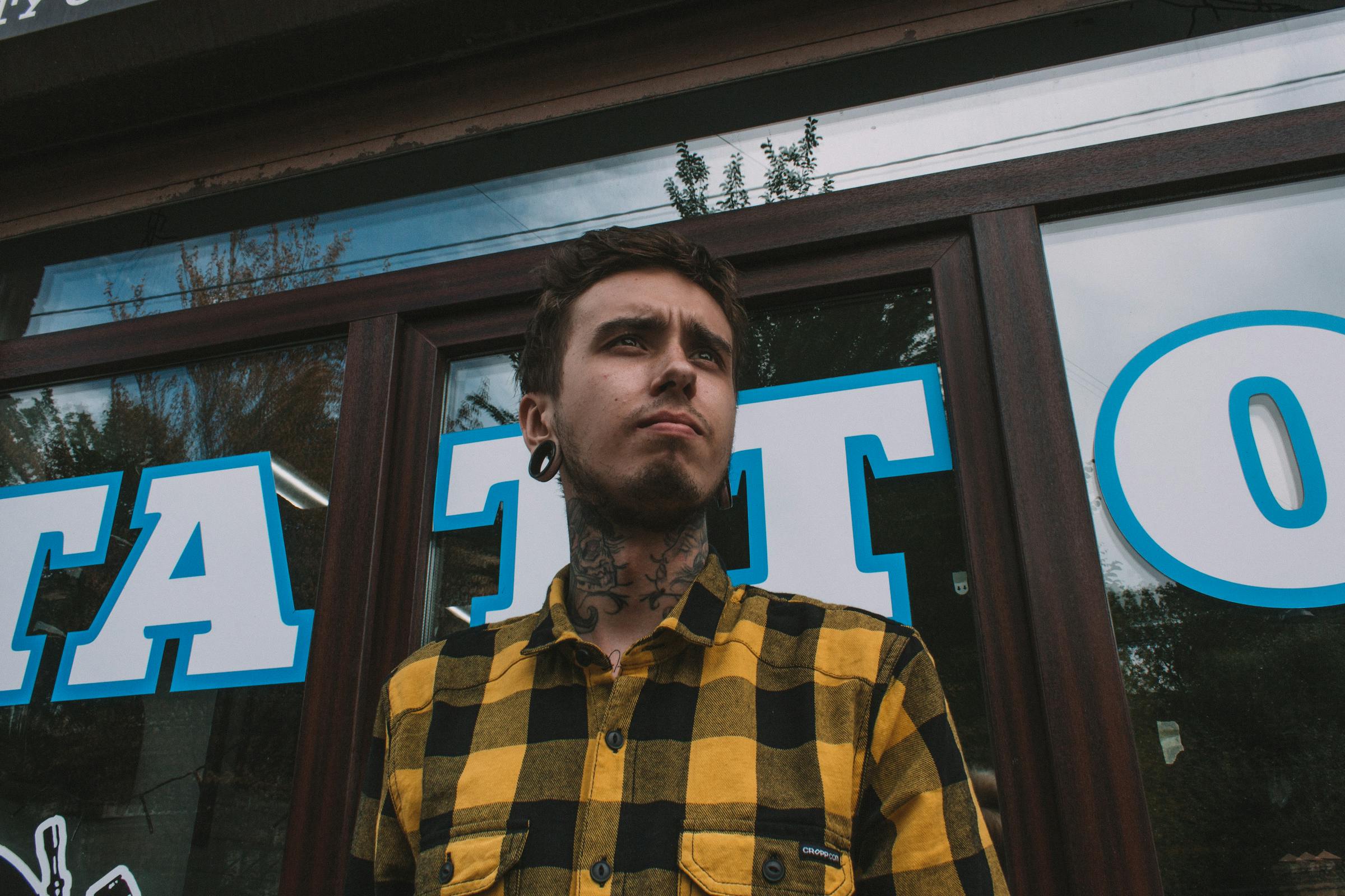 A tattooed man standing outside a tattoo shop | Source: Pexels
