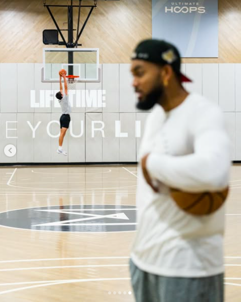 Karl-Anthony Towns stands directly in front of the camera as John "Jack" Edward Thomas Moynahan launches into a dunk in the background, posted on November 25, 2025. | Source: Instagram/karltowns